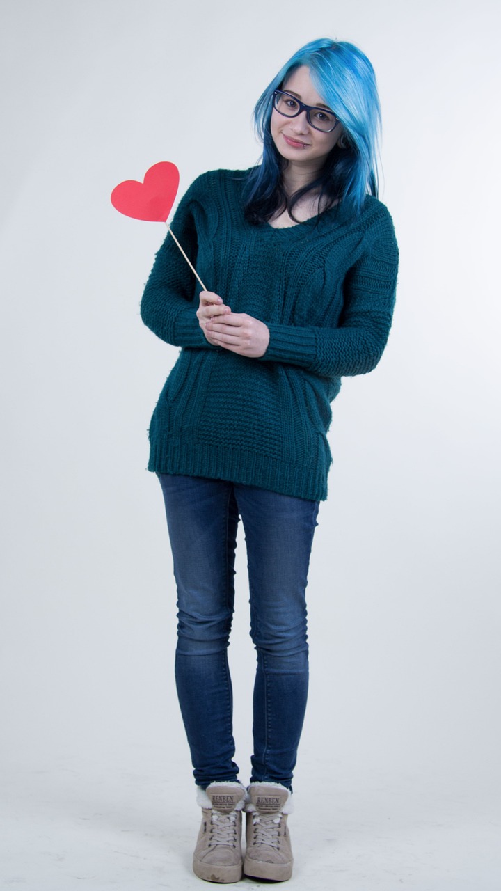 A happy woman holding a stick with a heart at the end | Source: Pexels