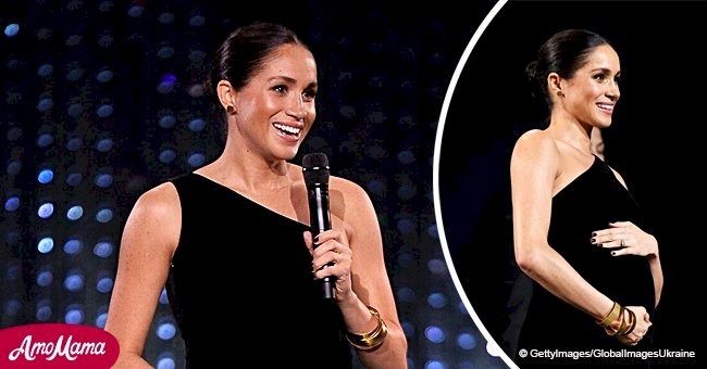 Meghan Markle cradles her huge baby bump in a one-shoulder dress during a surprise public outing