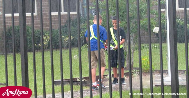 Teacher learns the truth in the pouring rain as two pupils hold national flag