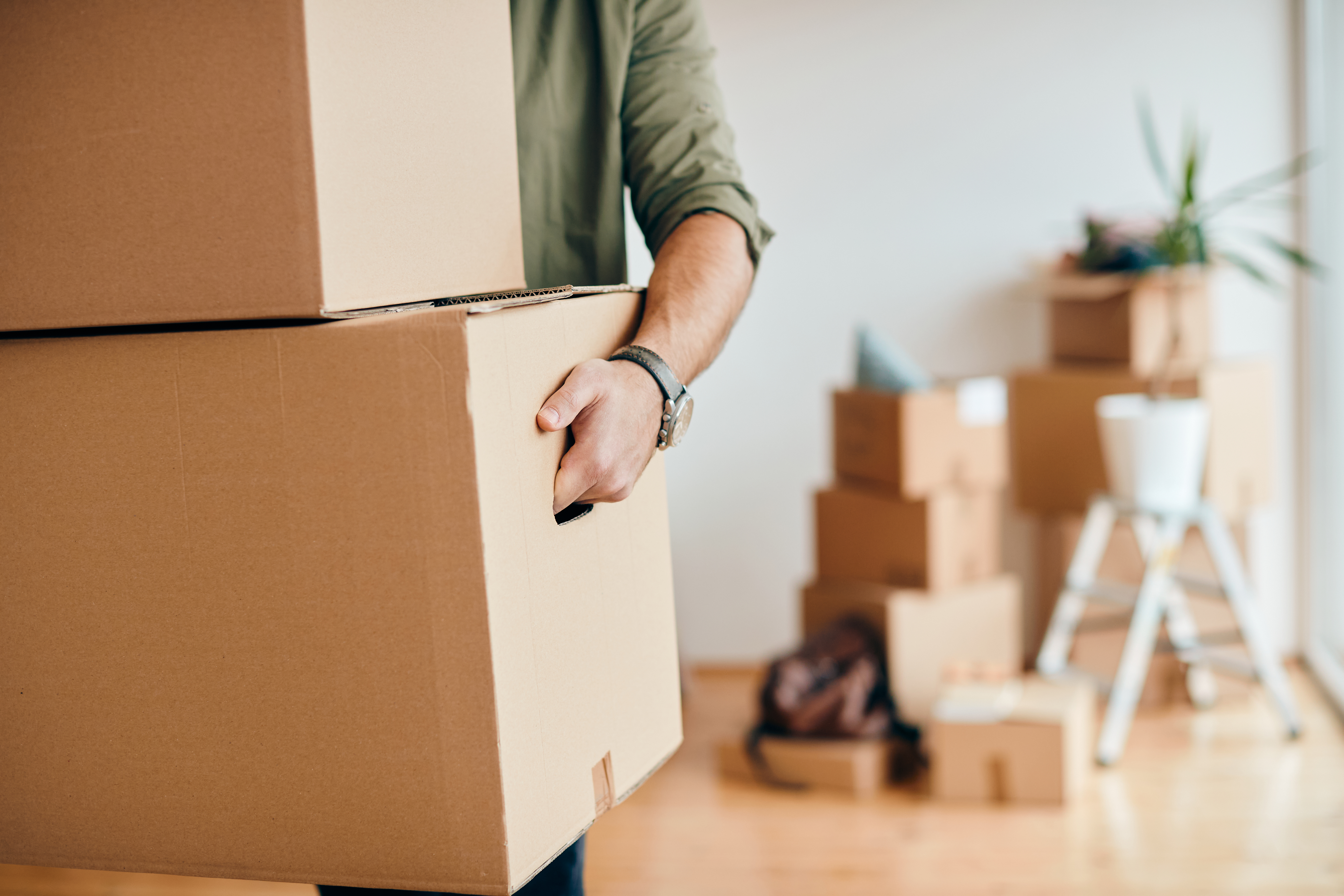 Close-up of a man with cardboard boxes moving into a new home | Source: Shutterstock