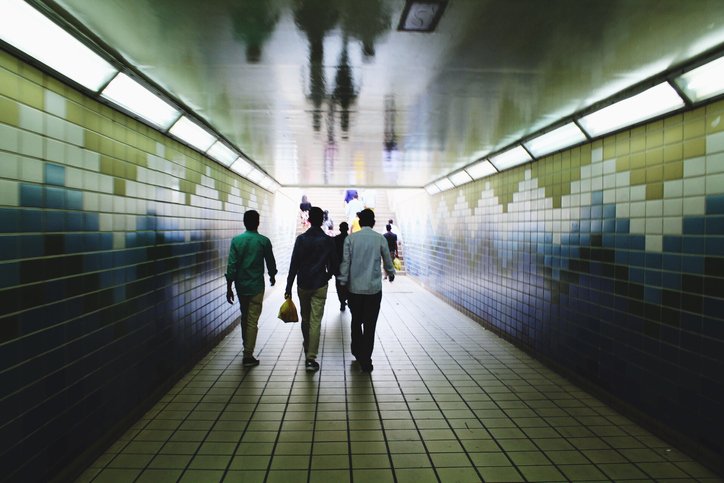 Drei Männer gehen zusammen in der U-Bahn-Station. | Quelle: Getty Images