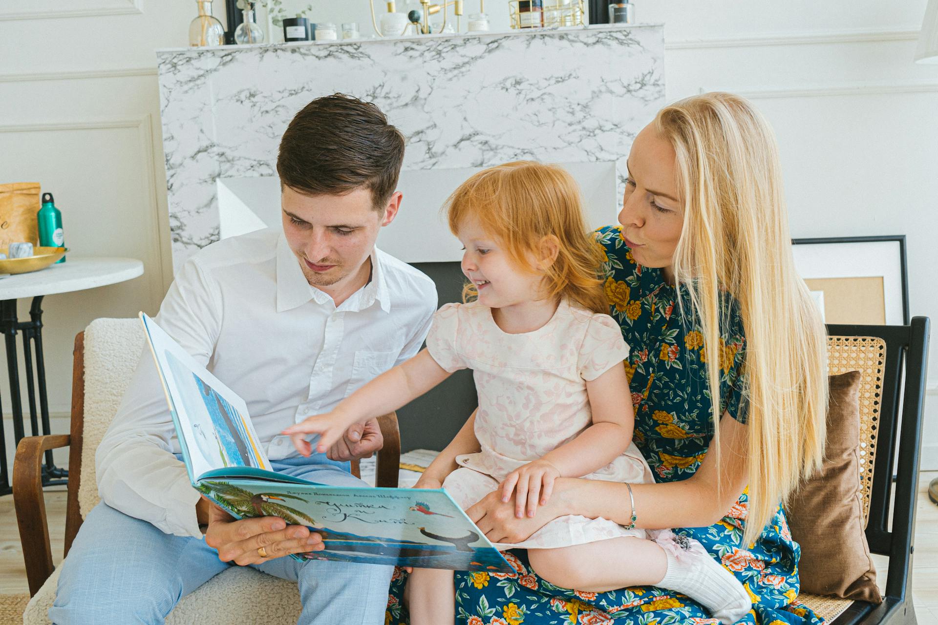 Parents reading a book to their little daughter | Source: Pexels