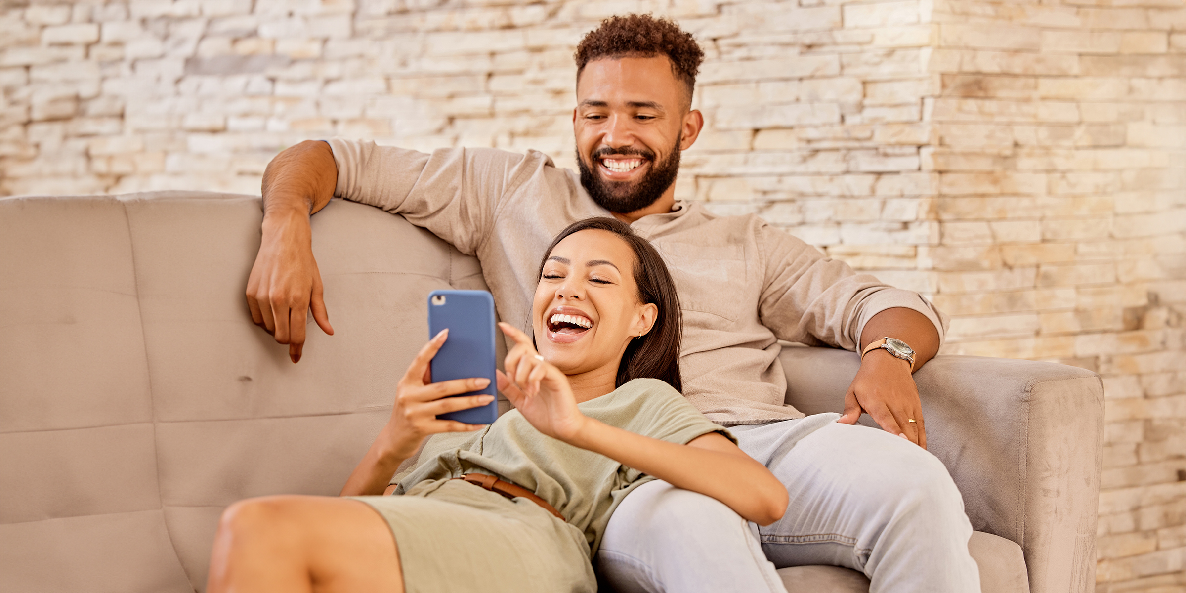 A couple laughing while looking at a phone screen | Source: Shutterstock