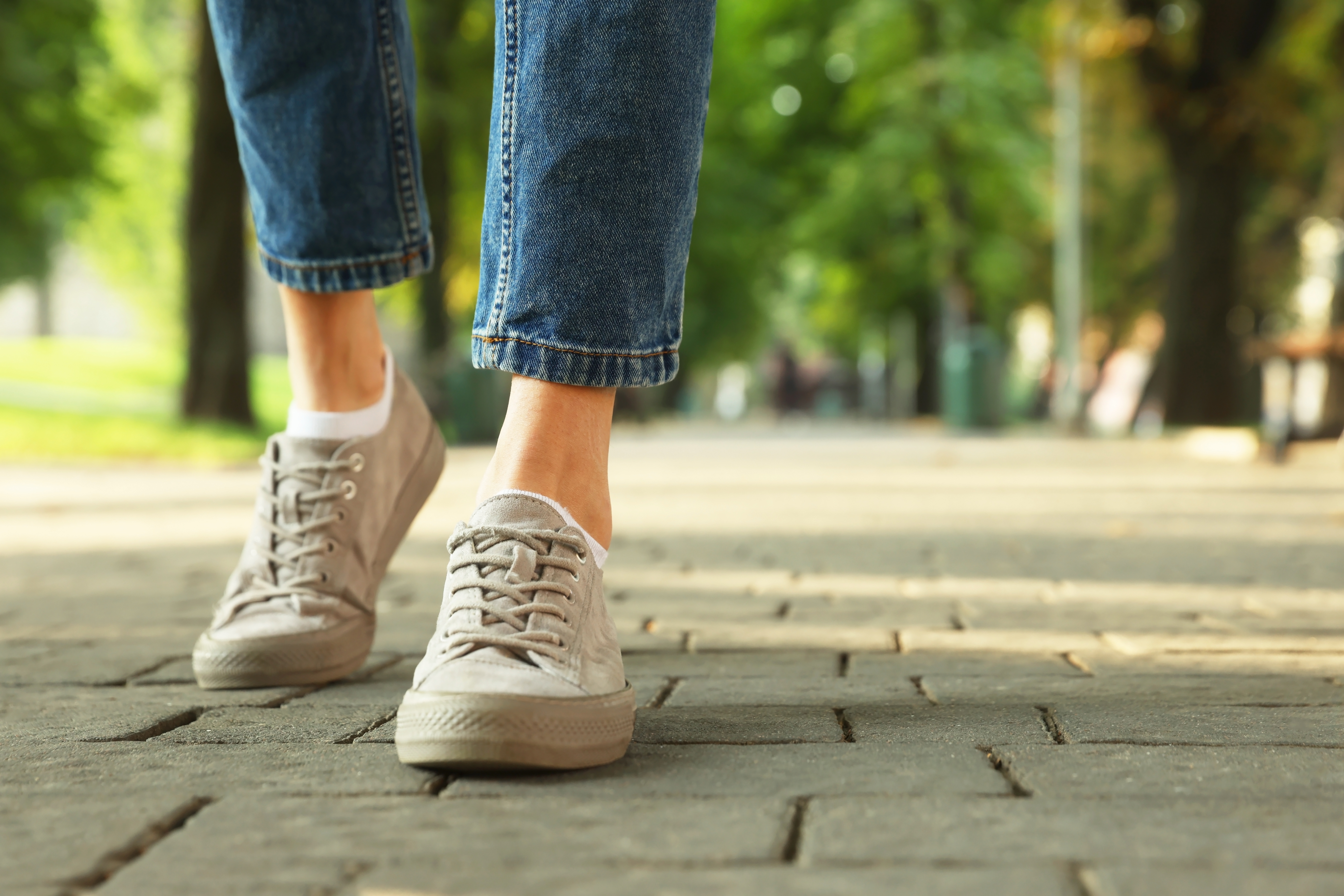 Woman in sneakers walking on city street. | Source: Shutterstock