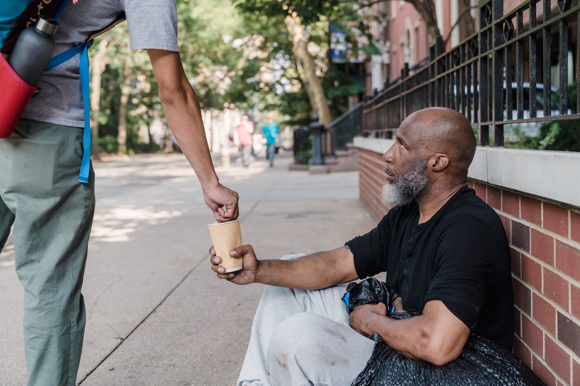Un indigente recibe unas monedas en un recipiente. | Foto: Pexels
