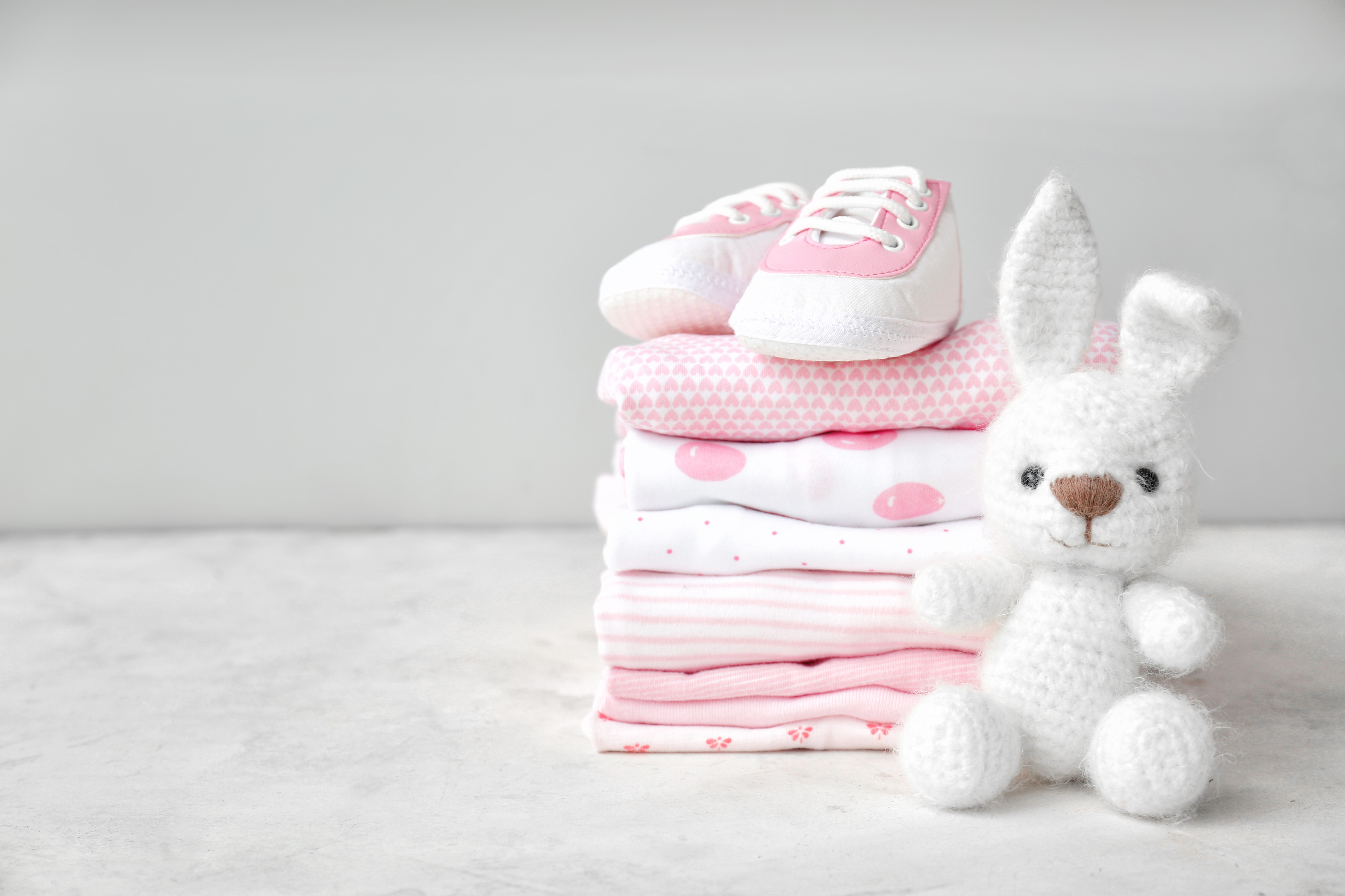 A stack of baby clothes, shoes, and a toy lying on a table | Source: Shutterstock