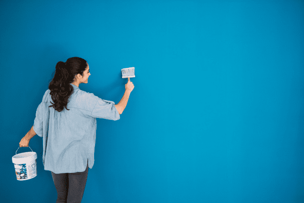 Joven pintando una pared azul. | Foto: Freepik