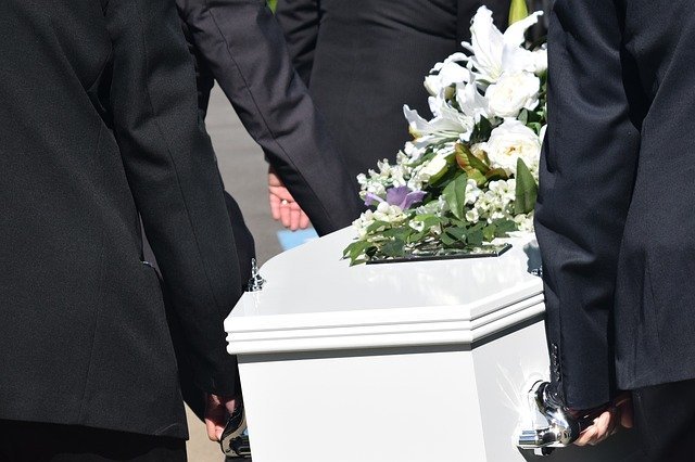 Pallbearers carry a white coffin with flowers on top | Photo: Pixabay