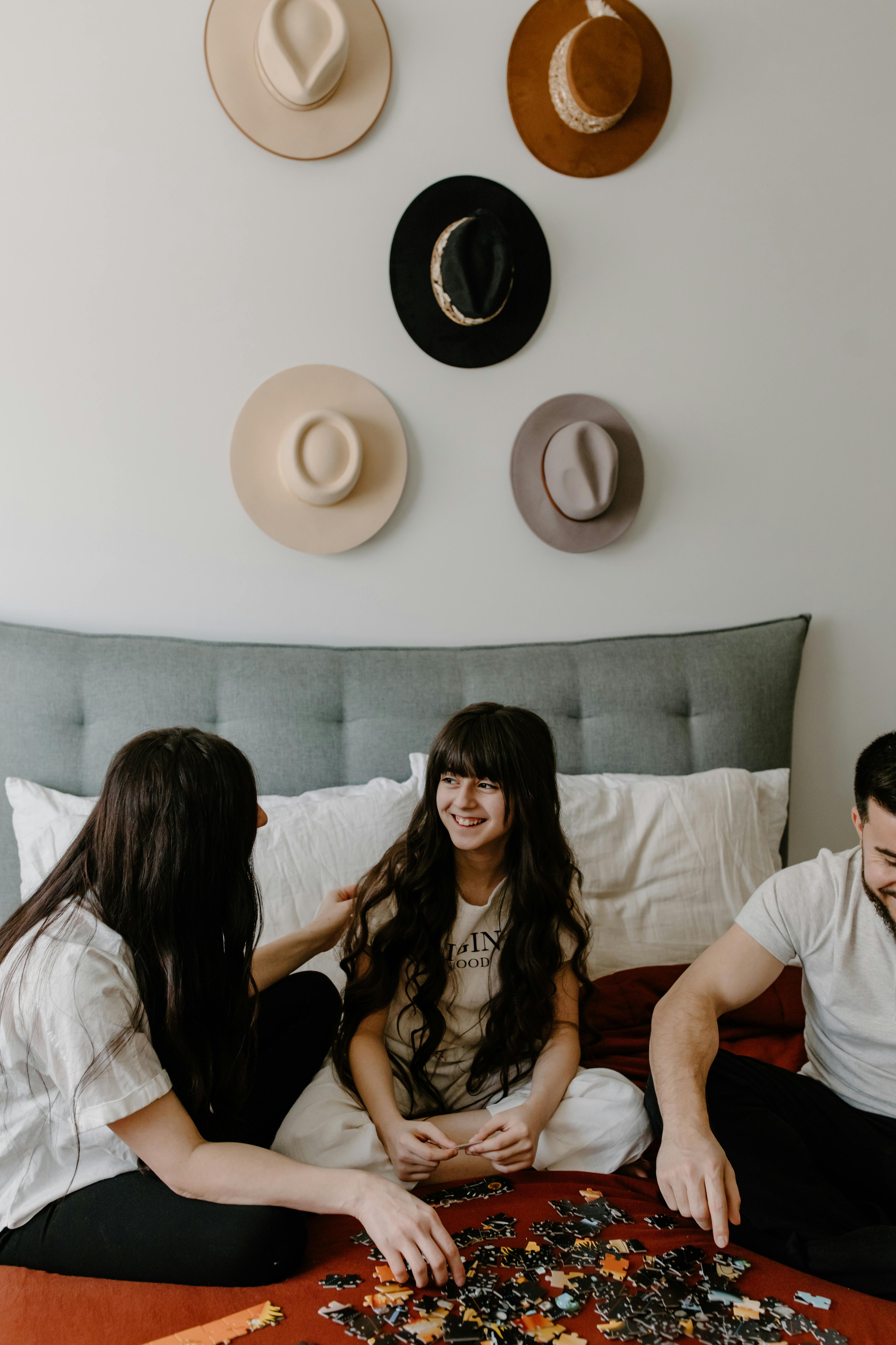 A happy family comprising of a father, a young girl, and a mother building a puzzle together | Source: Pexels