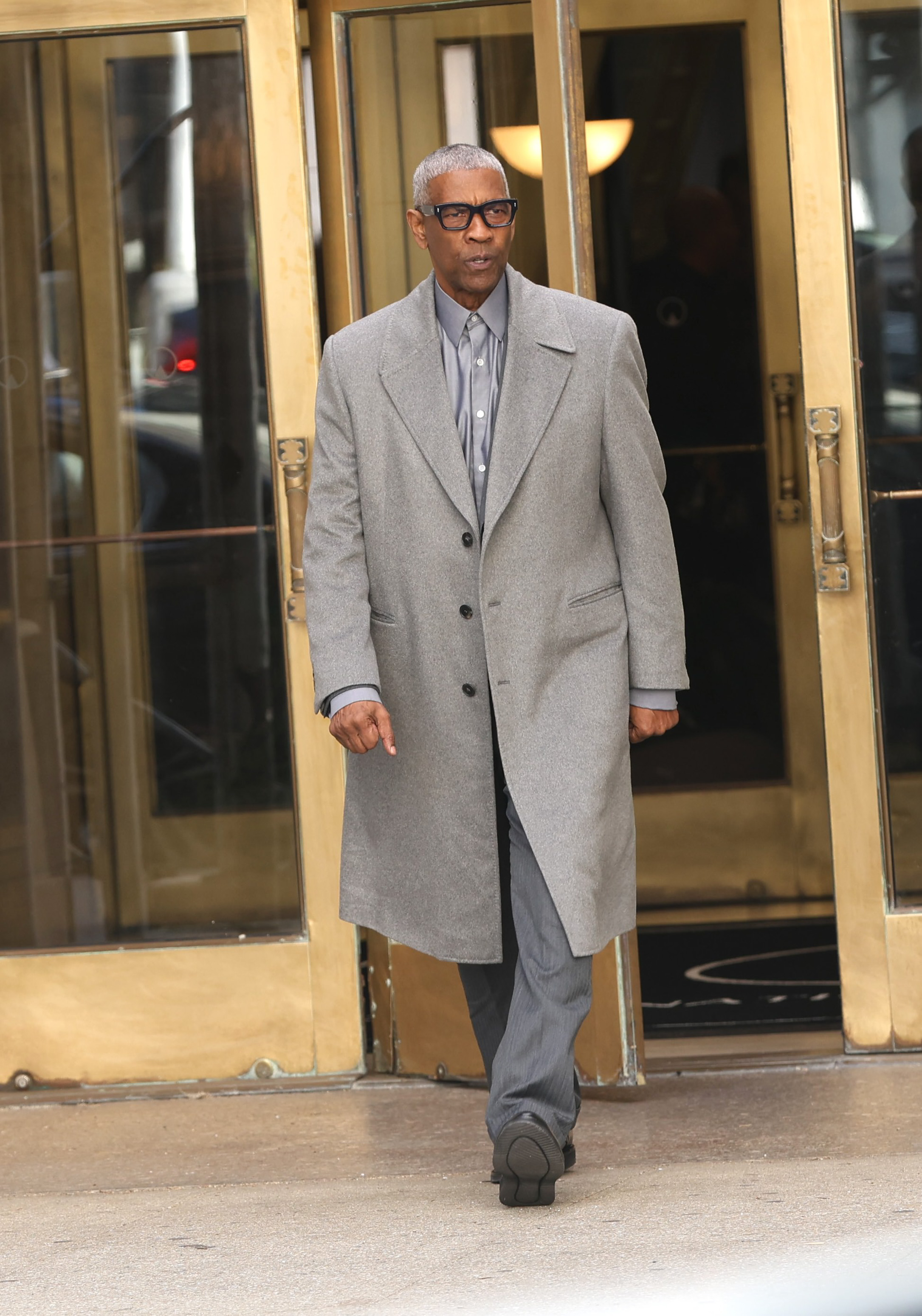 Denzel Washington steps out in Newark while filming "Here Comes the Flood." Sporting sleek gray hair, oversized glasses, and a sharp gray coat, his mature look instantly captivated fans as he strolled confidently on set.