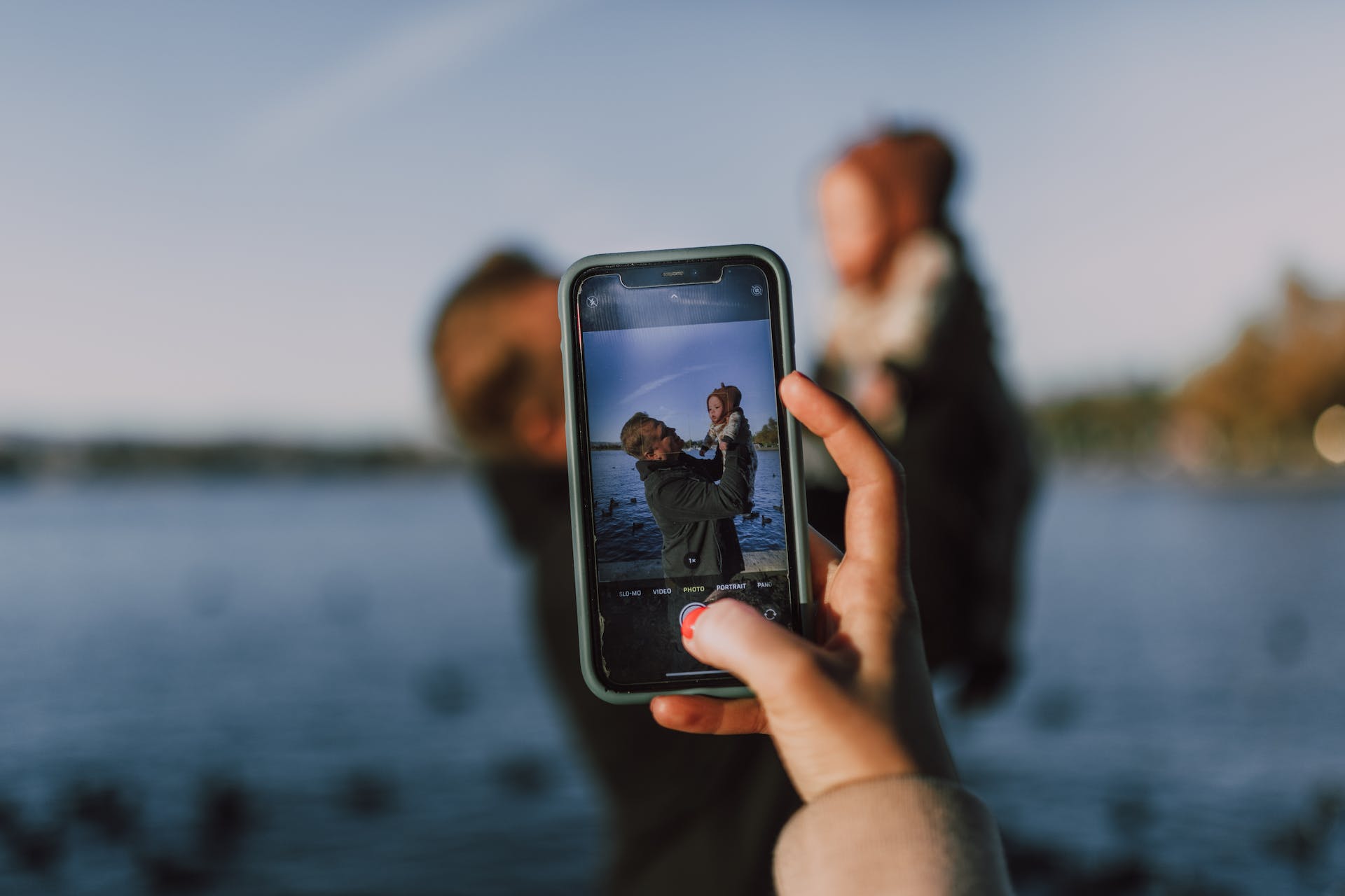 A woman taking a picture of a man holding a baby | Source: Pexels