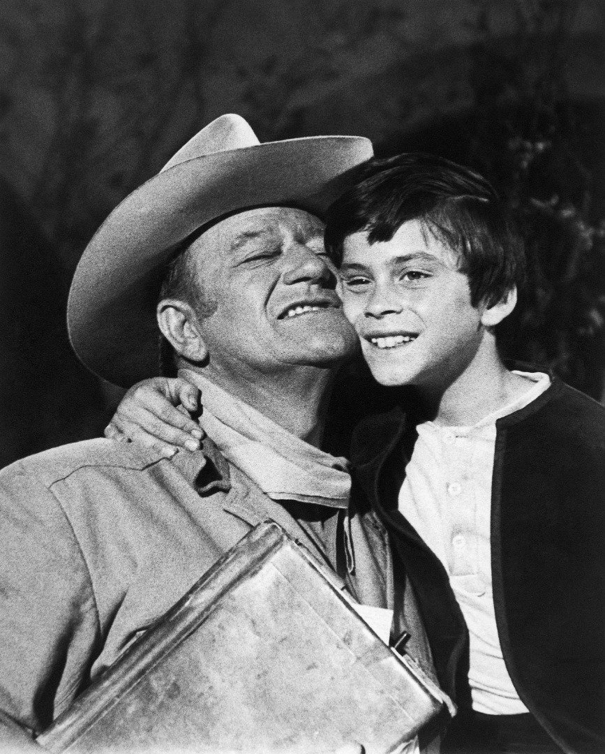 John Ethan Wayne, share a hug and some good words from Dad, John Wayne, after filming a shootout scene with outlaws in "The Million Dollar Kidnapping." | Source: Getty Images