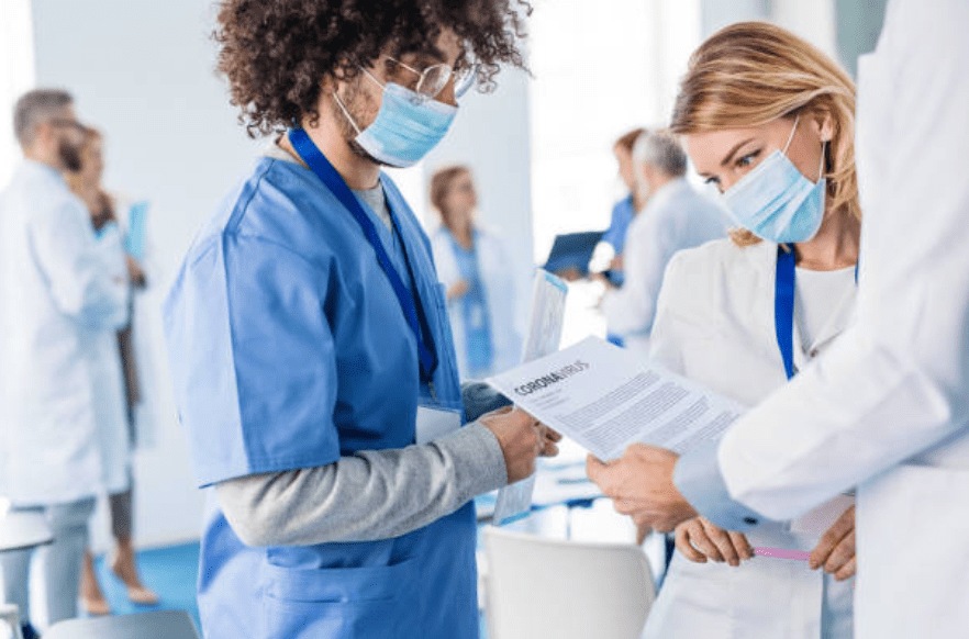 Doctors gather around a paper with the words coronavirus written at the top and appear to be having a discussion. | Photo: Getty Images