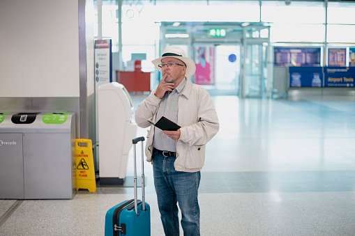  Photo of a elderly man standing in the airport terminal with his documentation, looking confusedly at the departure board | Photo: Getty Images