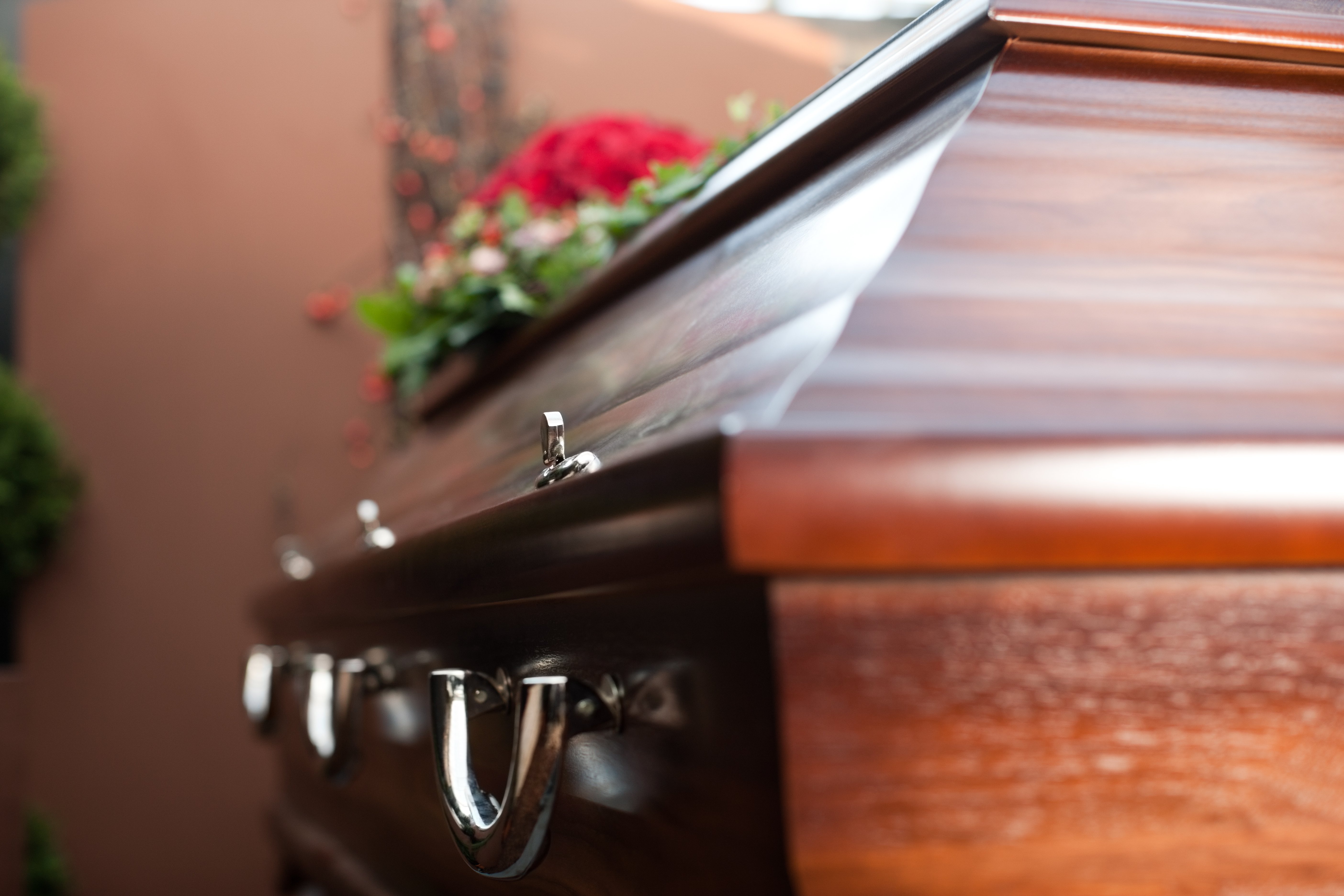 A coffin with red flowers on top. | Source: Shutterstock
