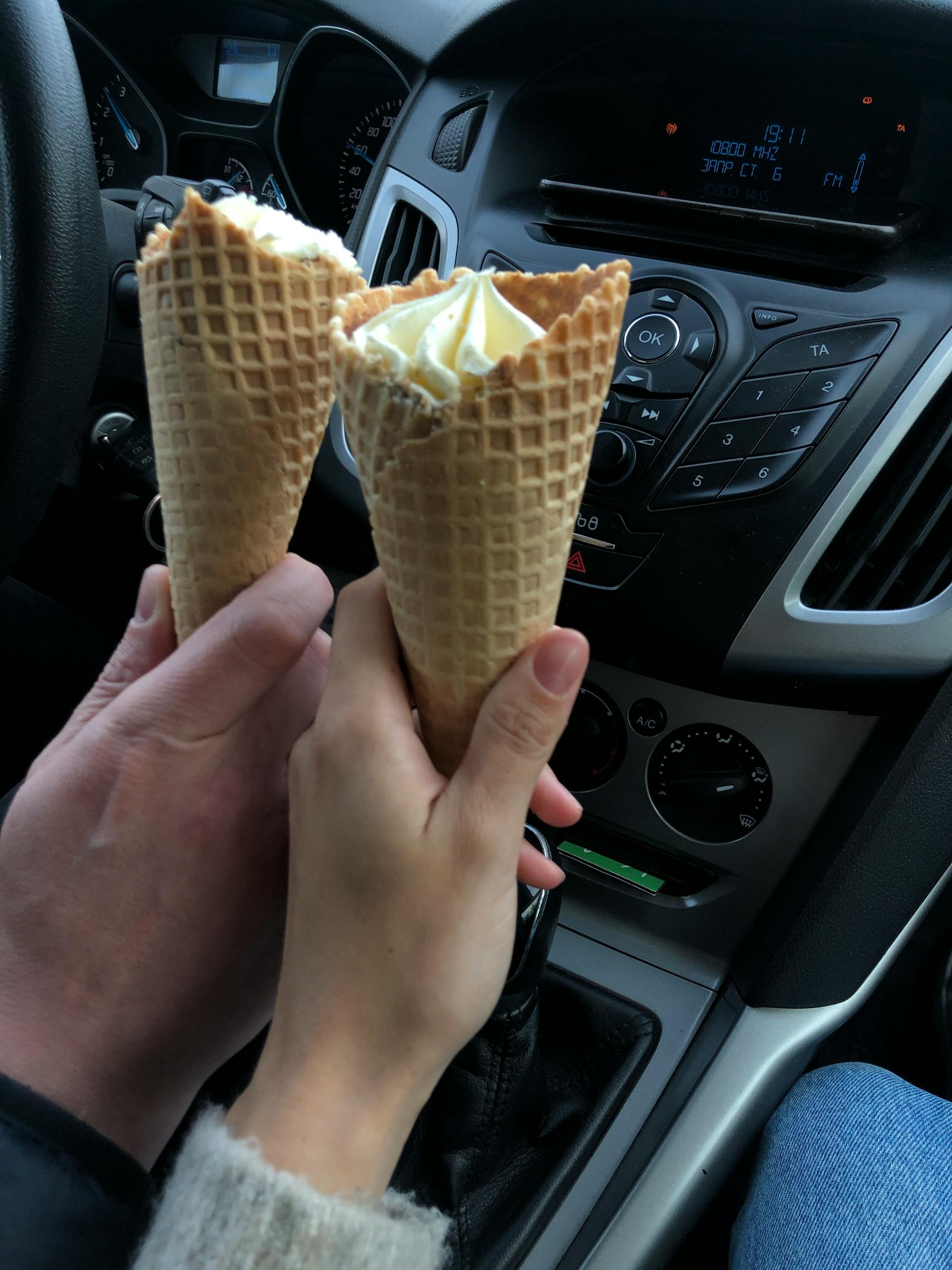 A couple holding ice cream cones in a car | Source: Pexels