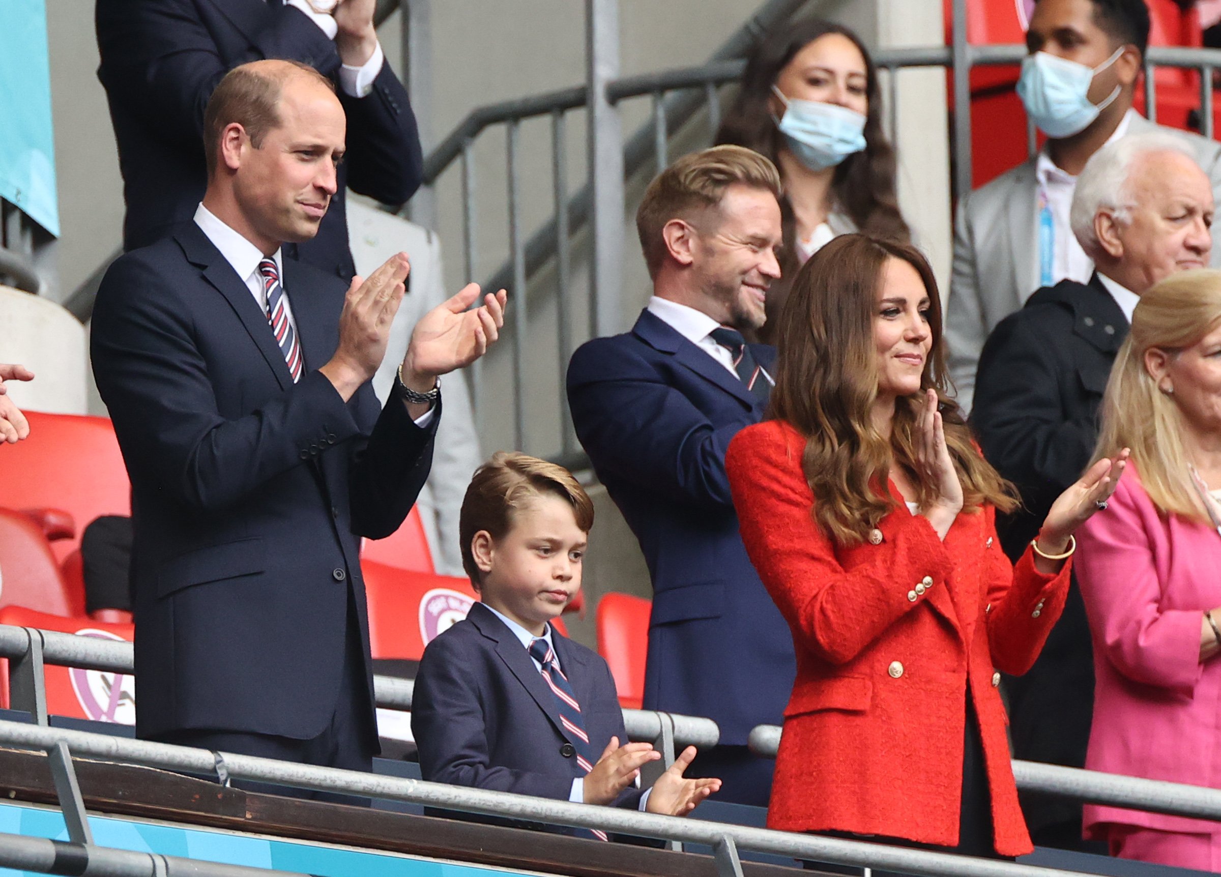 The British Prince William, Duke of Cambridge stands with his wife Kate, Duchess of Cambridge, and their son Prince George in the stands. | Source: Getty Images