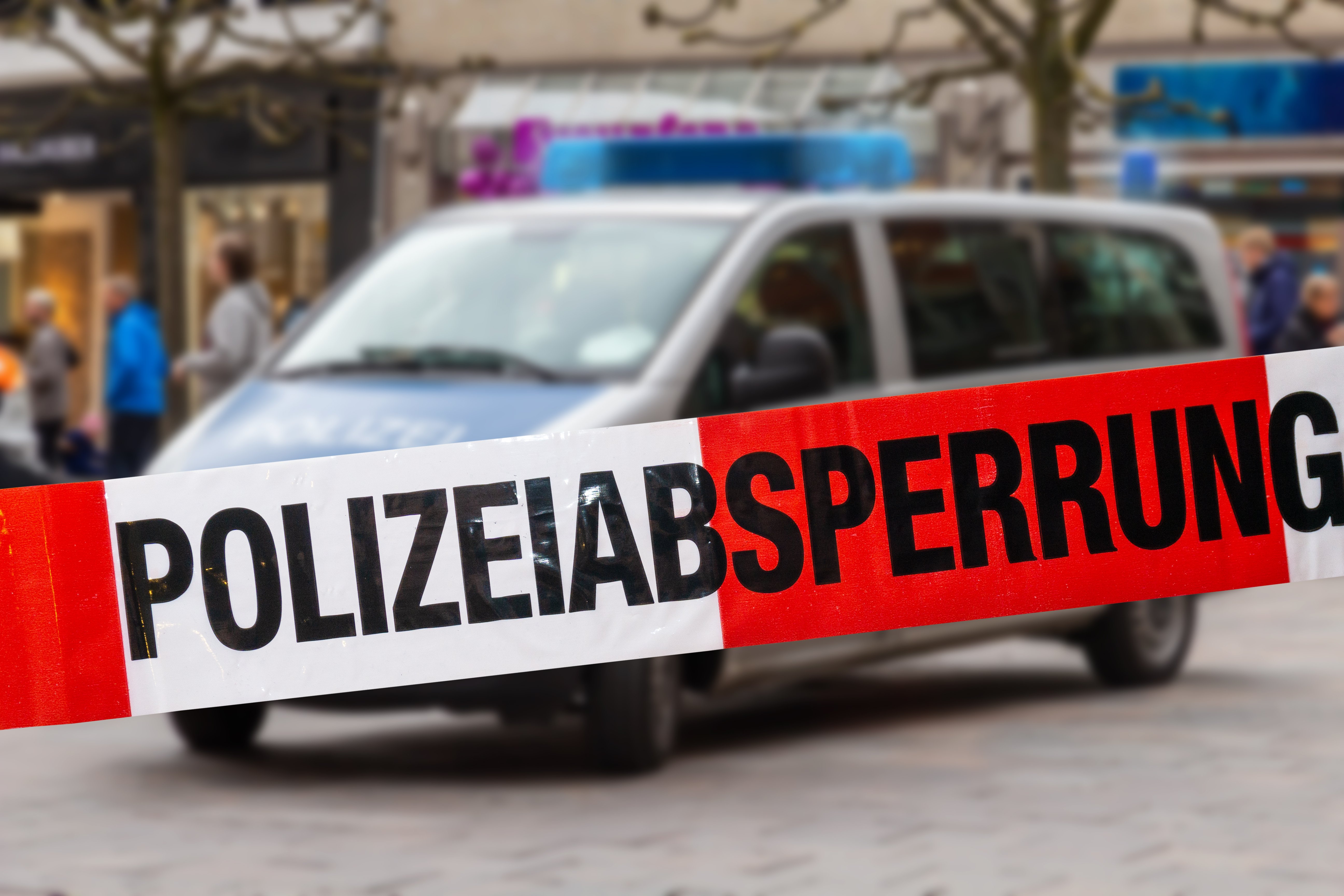 Deutsches Polizeiauto in der Stadt, das hinter Absperrband steht | Quelle: Shutterstock