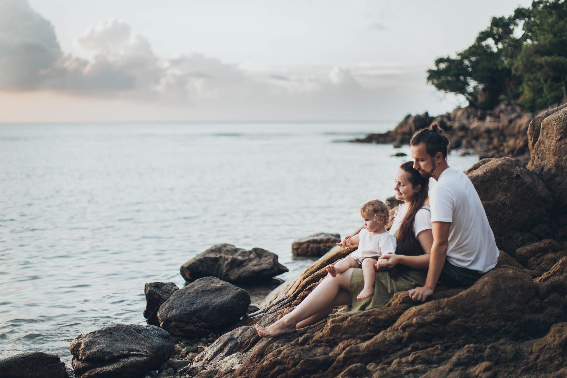 A couple sitting on rocks with their child | Source: Pexels