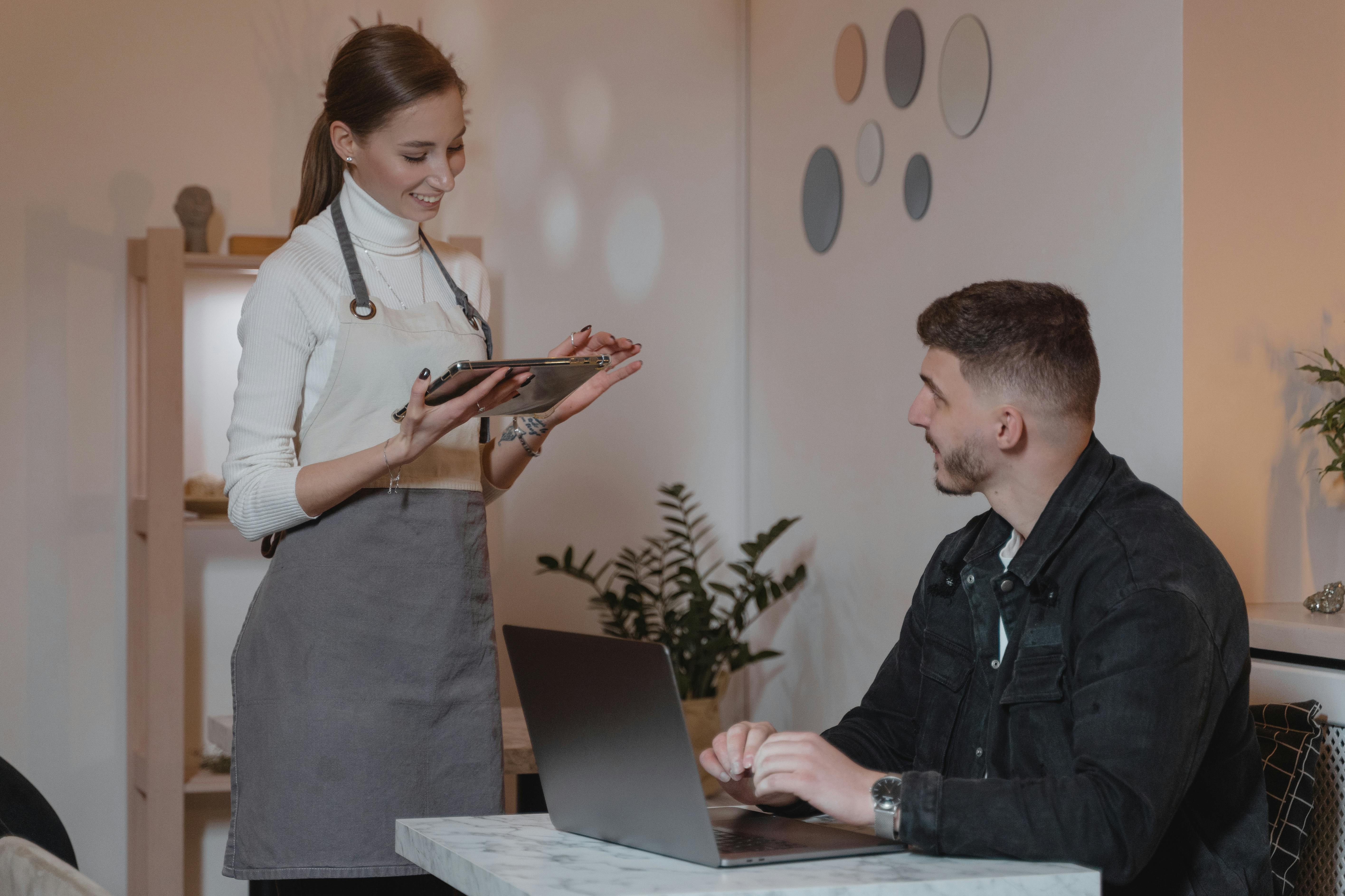 Woman in an apron talking to a male customer | Source: Pexels