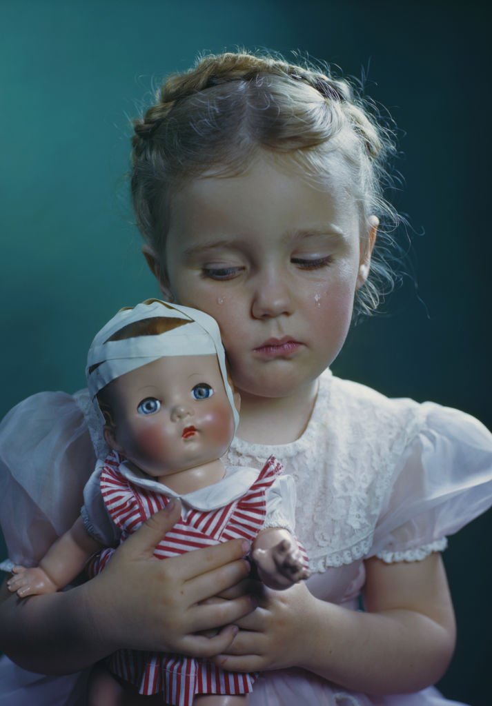 Une petite fille triste avec sa poupée. | Photo : Getty Images.