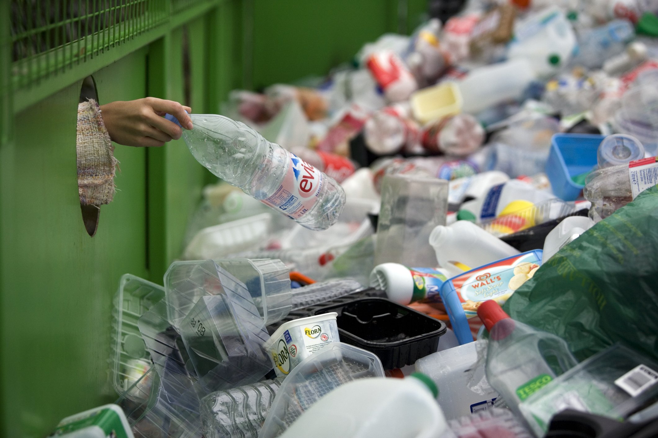 Eine Frau, die eine Plastikflasche in einem Papierkorb abstellt | Quelle: Getty Images
