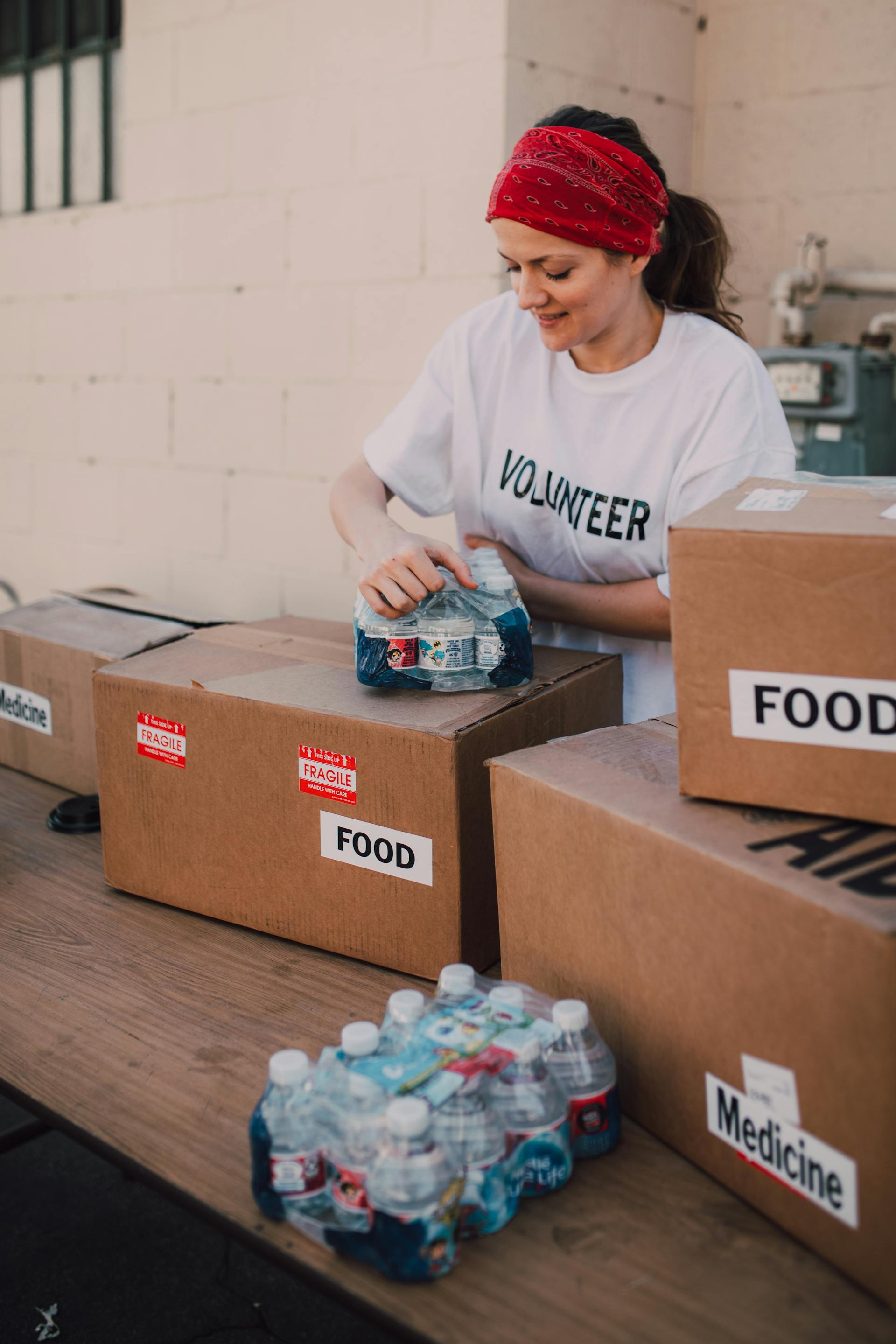A woman volunteer holding drink bottles on top of a brown box | Source: Pexels 6646