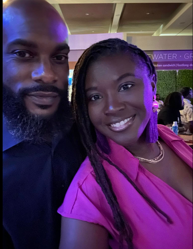 Nancy Metayer Bowen and her husband, Stephen Bowen, pose for a close-up selfie under soft, colorful lighting, both smiling warmly as she wears a bright pink top and statement earrings, capturing a relaxed night-out moment. | Source: Facebook/Nancy Metayer Bowen