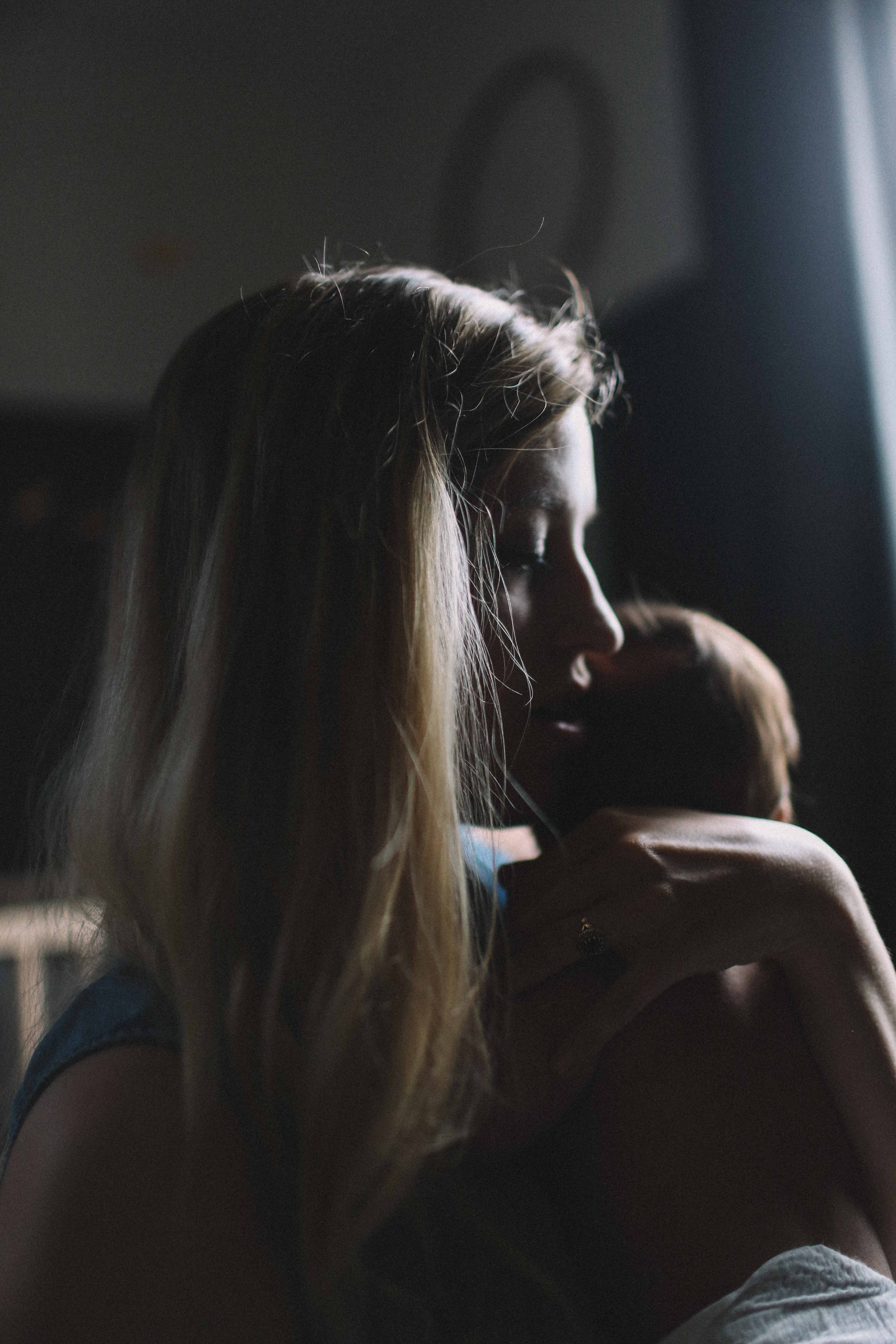 A young mum cuddling her newborn | Photo by Jenna Norman on Unsplash