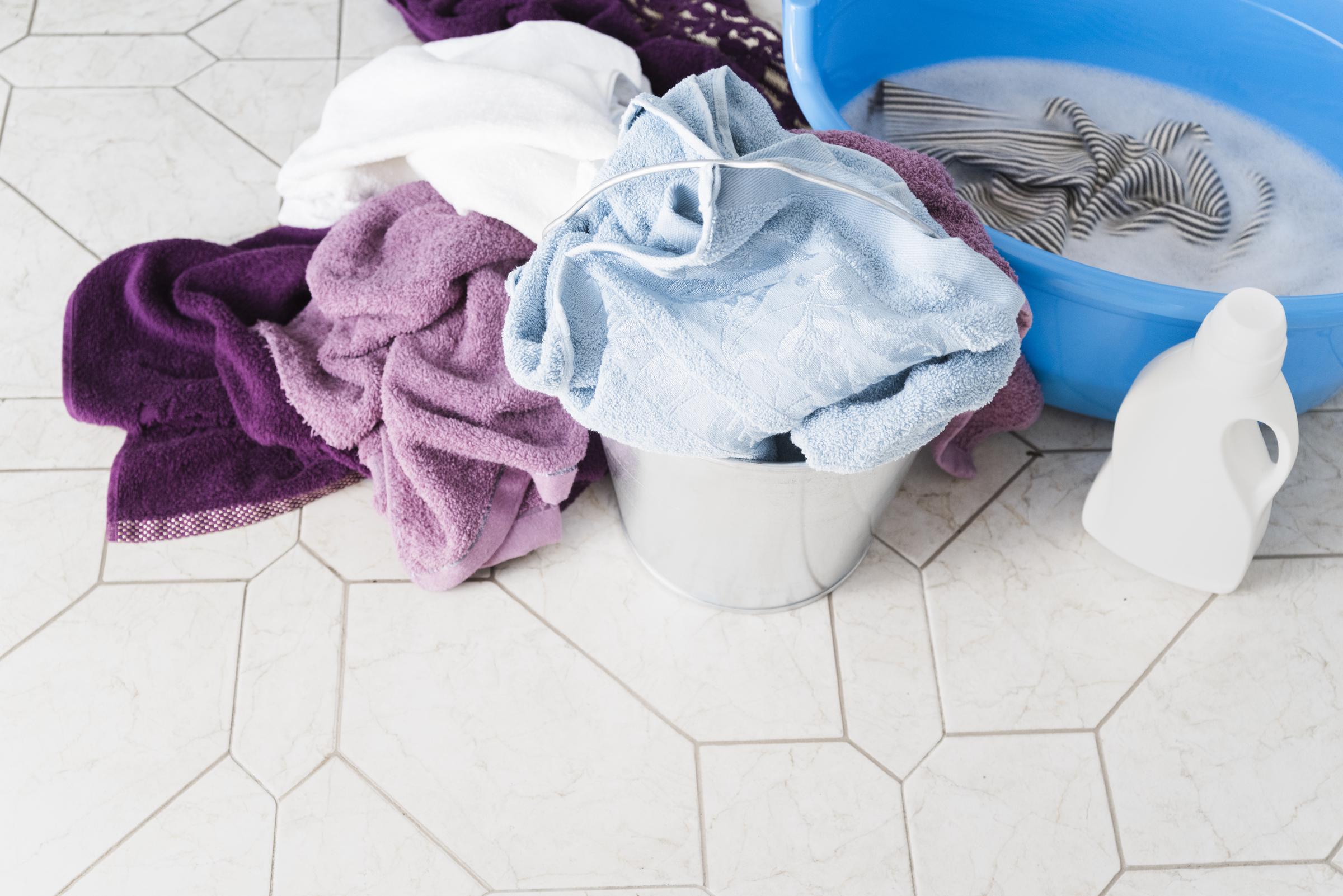 A pile of clothes and detergent near a laundry basket | Source: Freepik