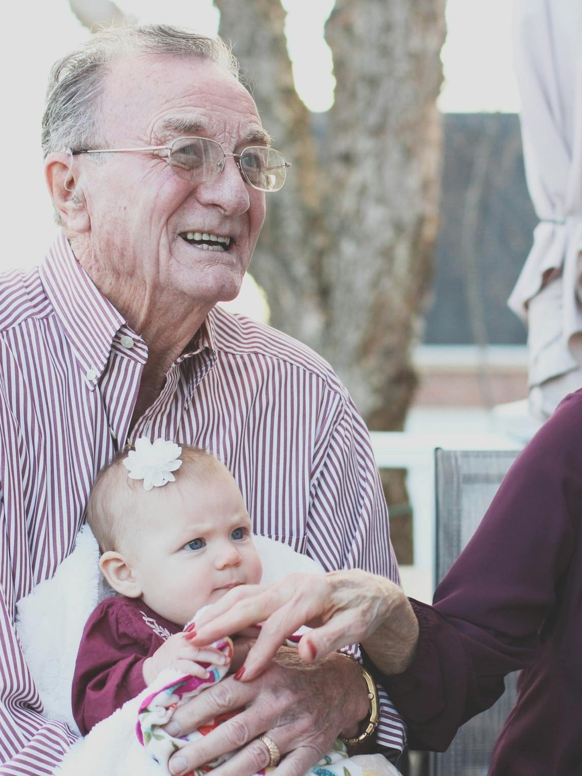 An elderly man holds a baby on his lap | Source: Pexels