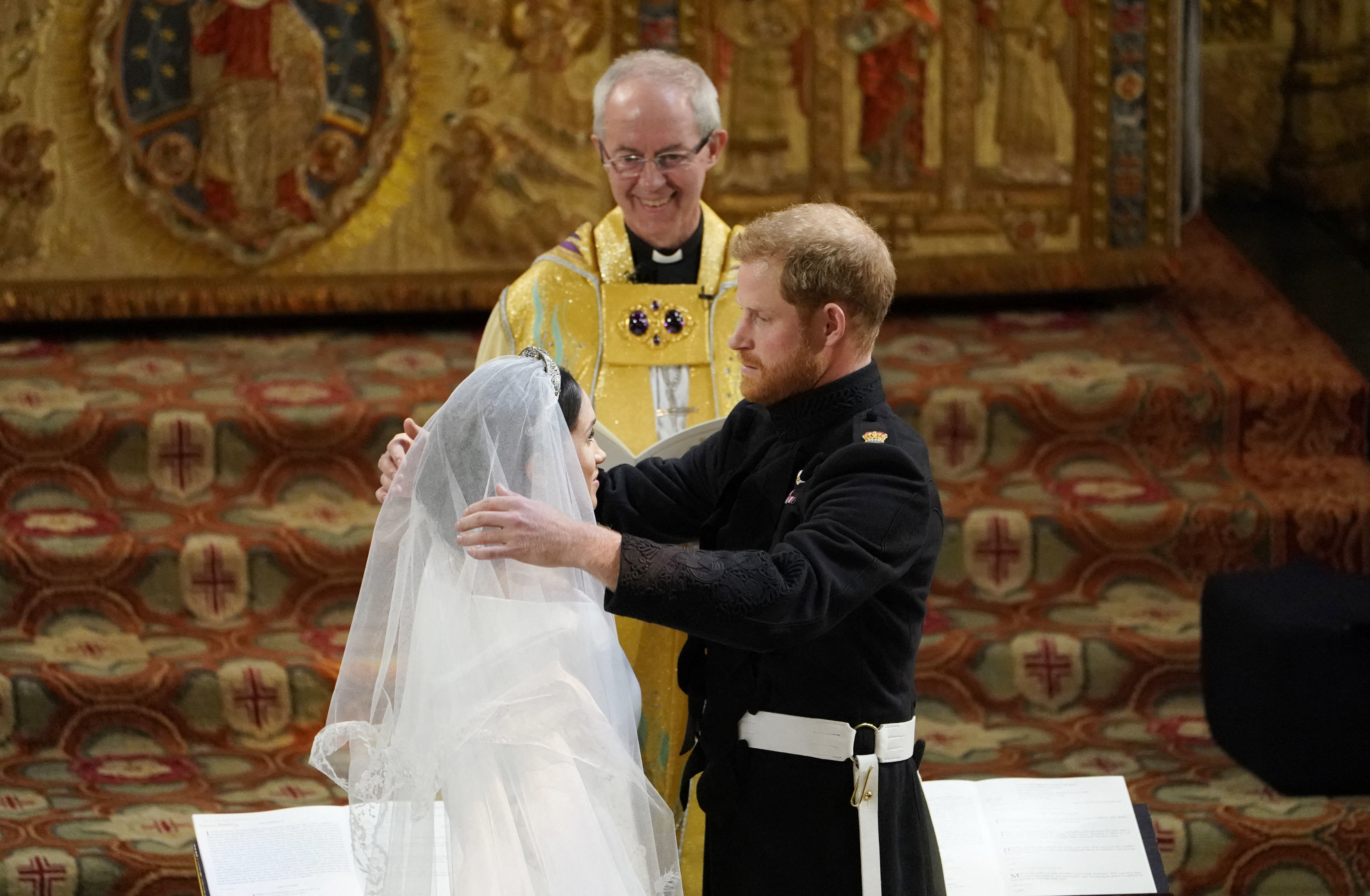 Prince Harry removes the veil of Meghan Markle before Archbishop of Canterbury Justin Welby (C) in St George's Chapel, Windsor Castle, in Windsor, on May 19, 2018. | Source: Getty Images