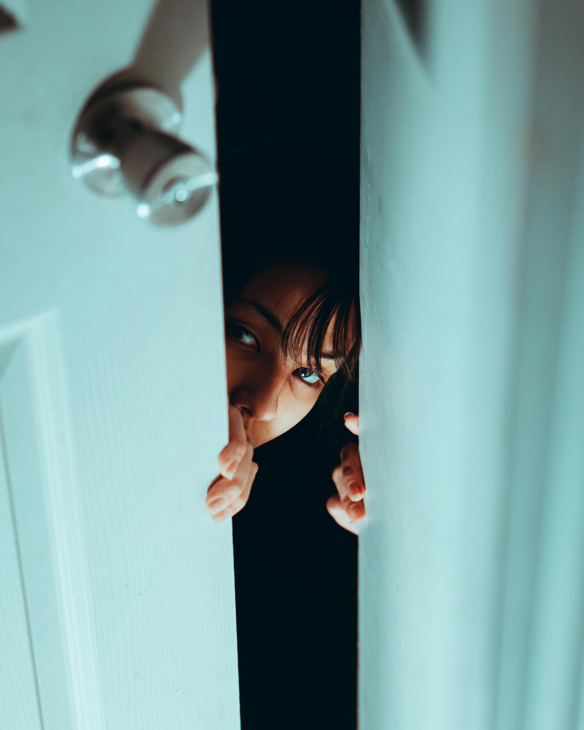 A closeup shot of a woman peeking through the door | Source: Pexels