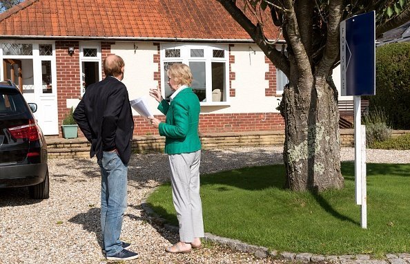 Potential house buyers pictured viewing a house with a for sale sign | Photo: Getty Images