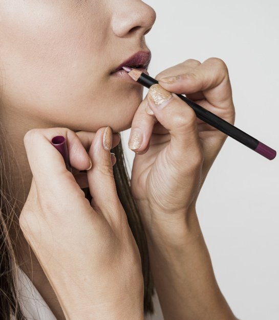 Estilista aplicando delineador de labios. │Foto: Freepik