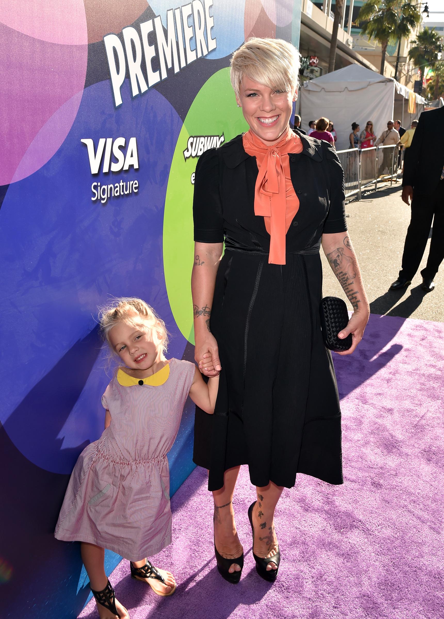 Pink and Willow Sage Hart hold hands at Disney-Pixar's "Inside Out" premiere at the El Capitan Theatre on June 8. Pink smiles in a black dress with an orange scarf as little Willow poses in a striped dress.