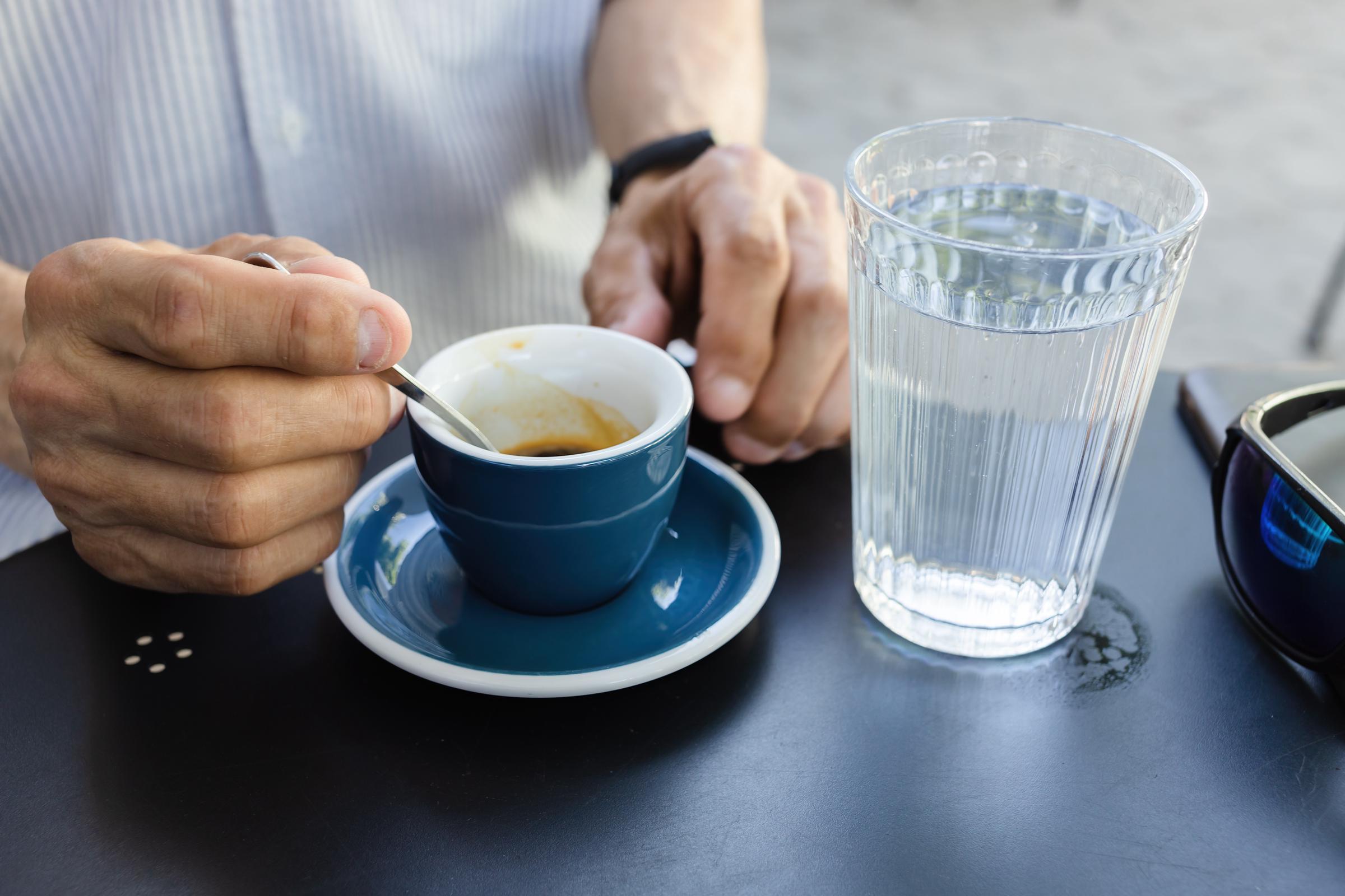 A half-empty cup of coffee beside a full glass of water | Source: Shutterstock