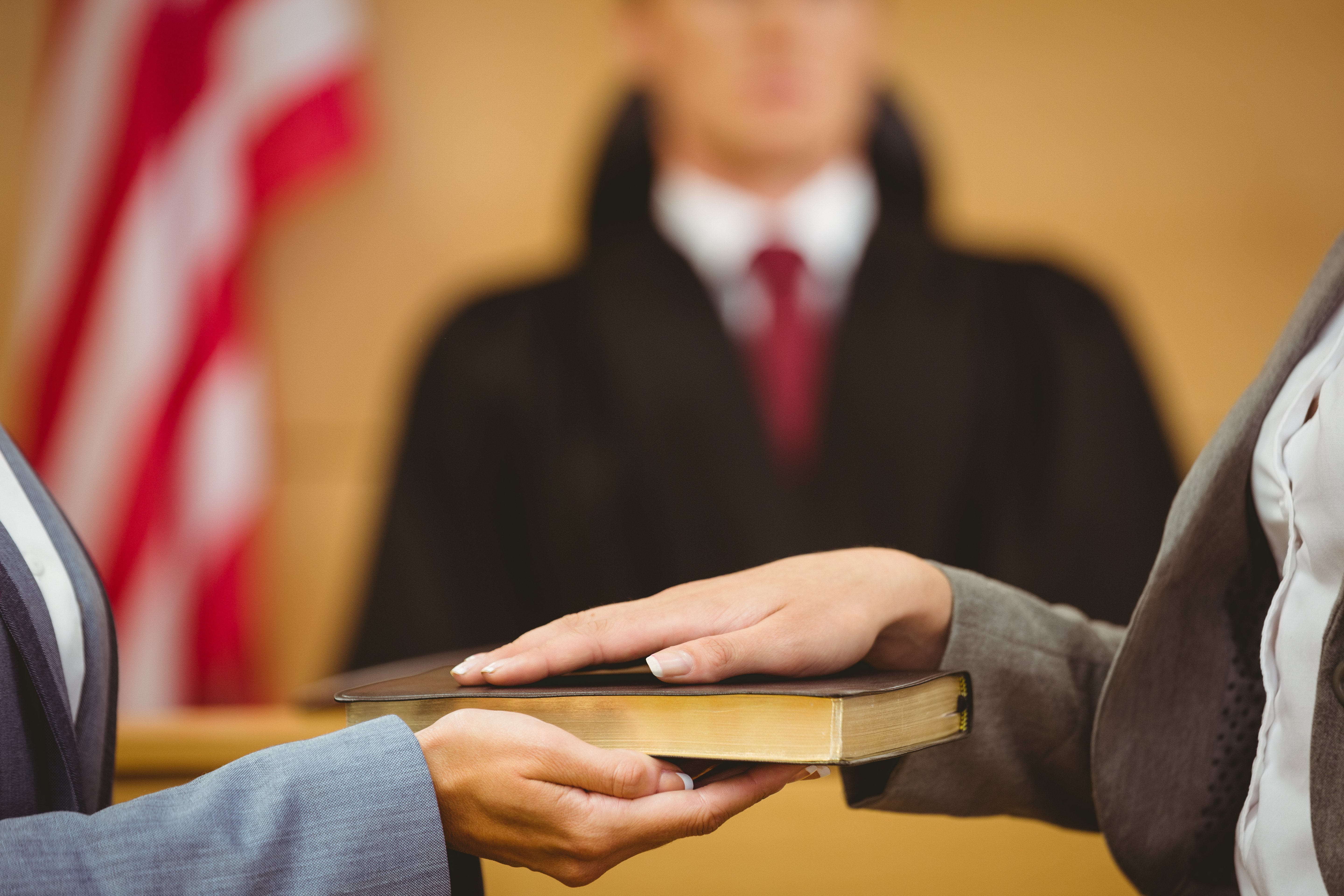 Witness swearing on bible in court. Image Shutterstock