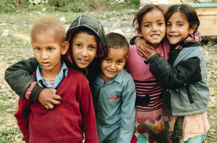 Des groupes d'enfants qui rient fixant le caméra | Photo : Unsplash