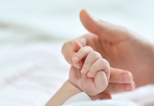 Mujer tomando de la mano a bebé. │Foto: Freepik