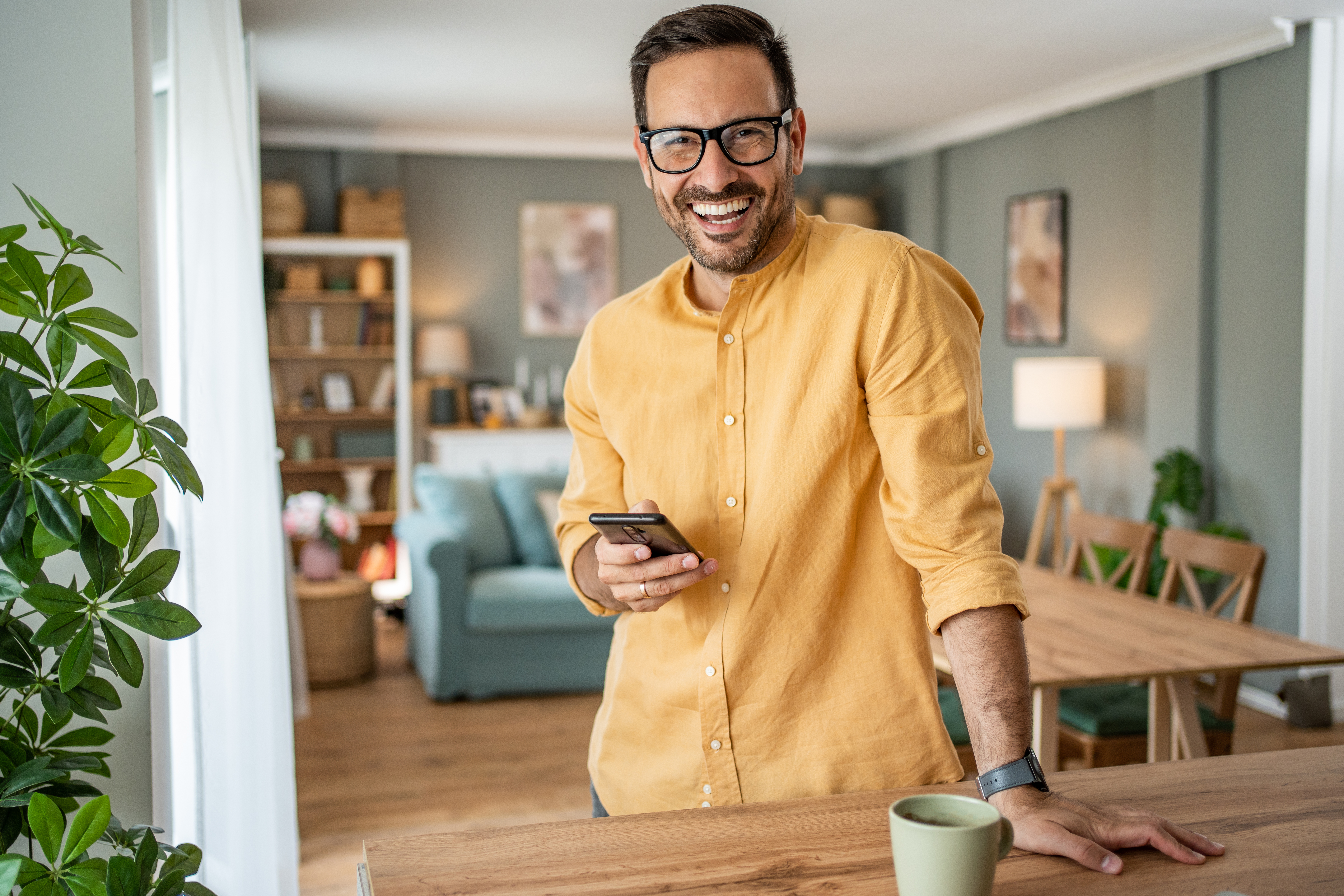 Portrait of cheerful man using smartphone at home | Source: Getty Images
