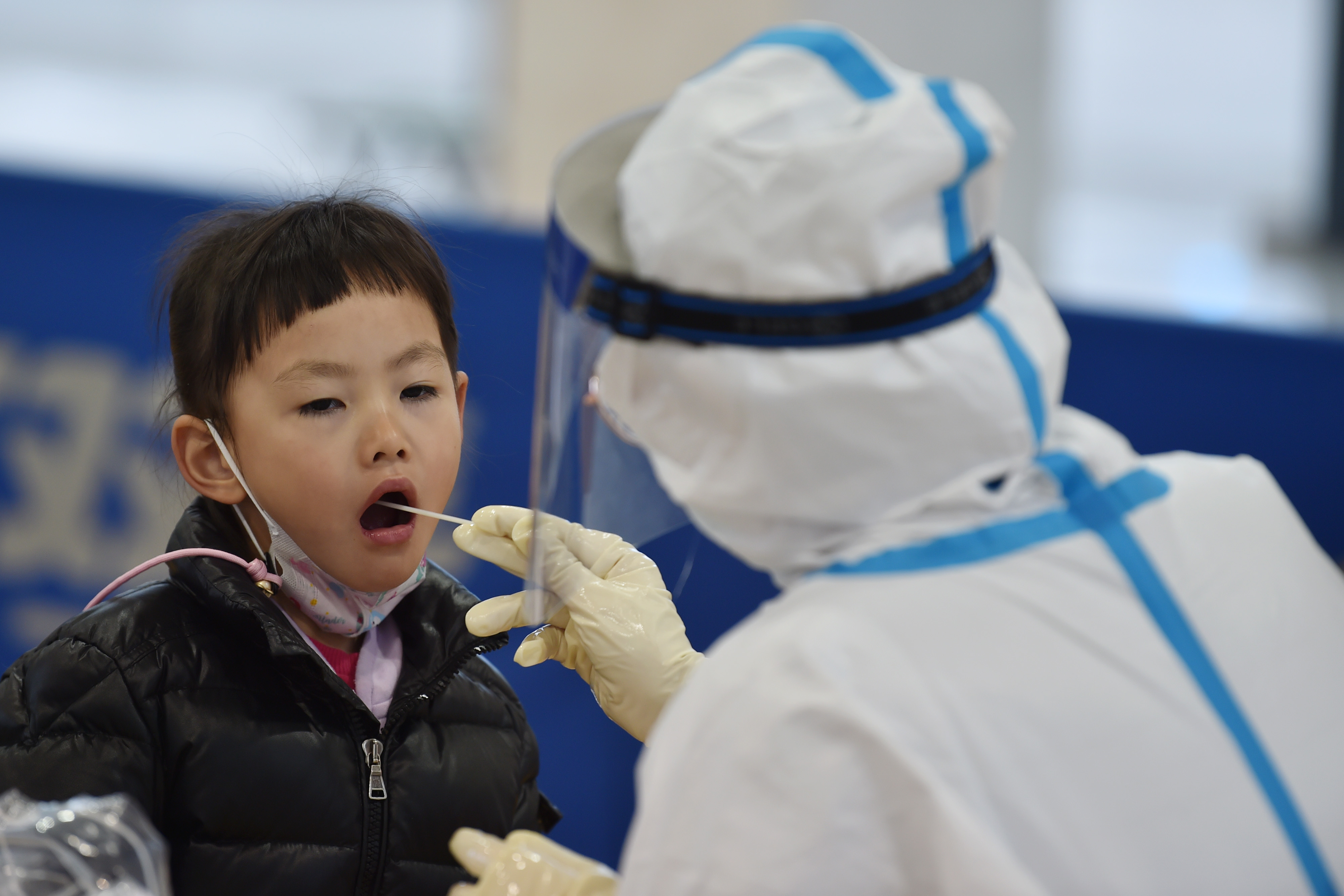 A medical worker takes throat swab samples from a child | Source: Getty Images
