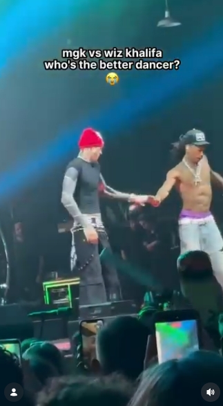 MGK reaches toward Wiz Khalifa as the pair continue their playful dance battle onstage in Charlotte. The moment appeared to show the rapper jokingly passing a dance move to Khalifa before his collaborator responded with a routine of his own. | Source: Instagram/mgkmagic
