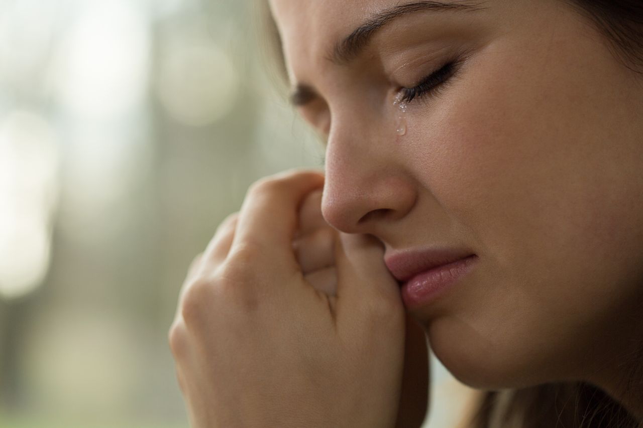 A woman in tears while looking outside the window. | Source: Shutterstock