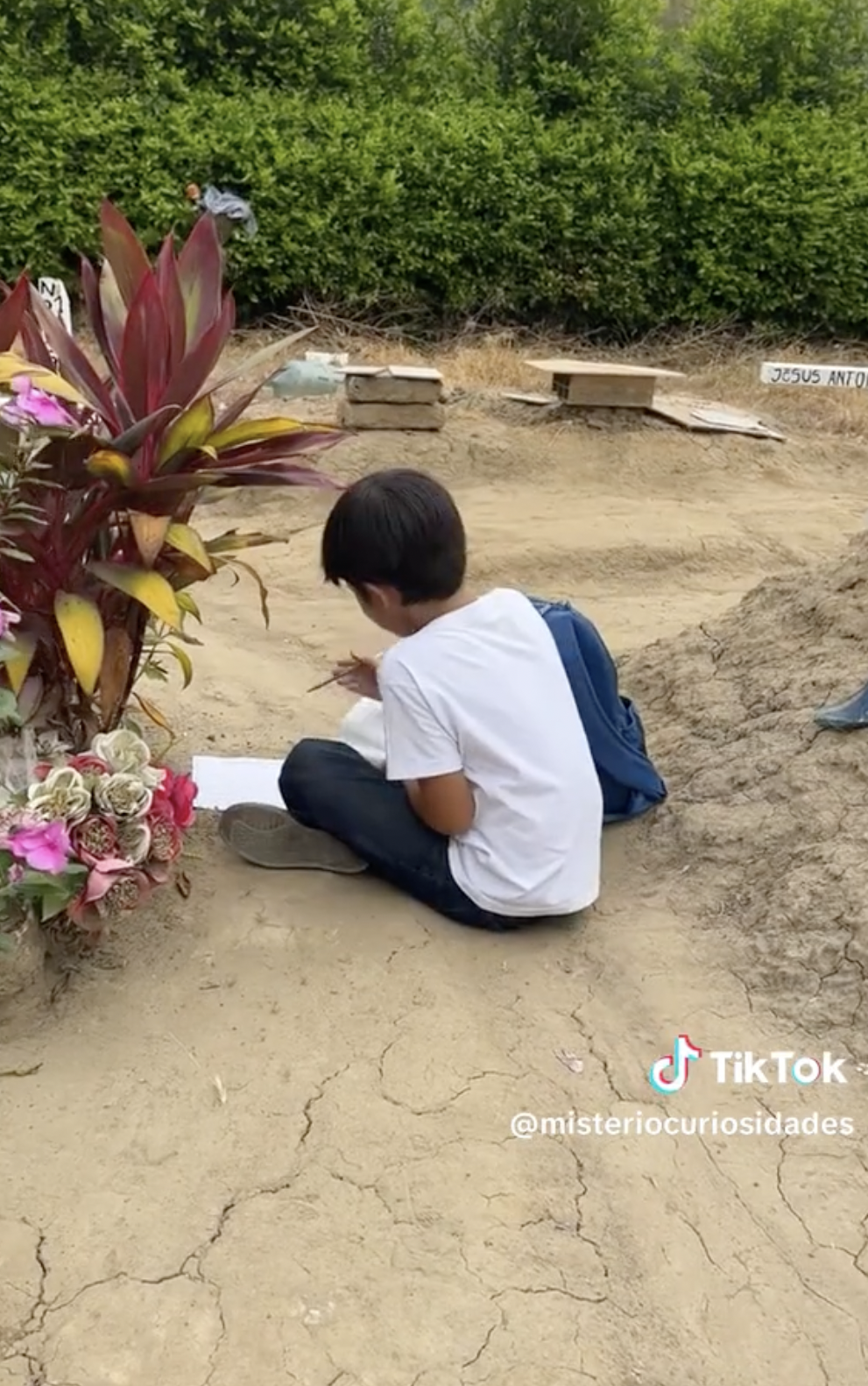 Kike doing his homework at his late mother's grave. | Source: tiktok.com/@misteriocuriosidades