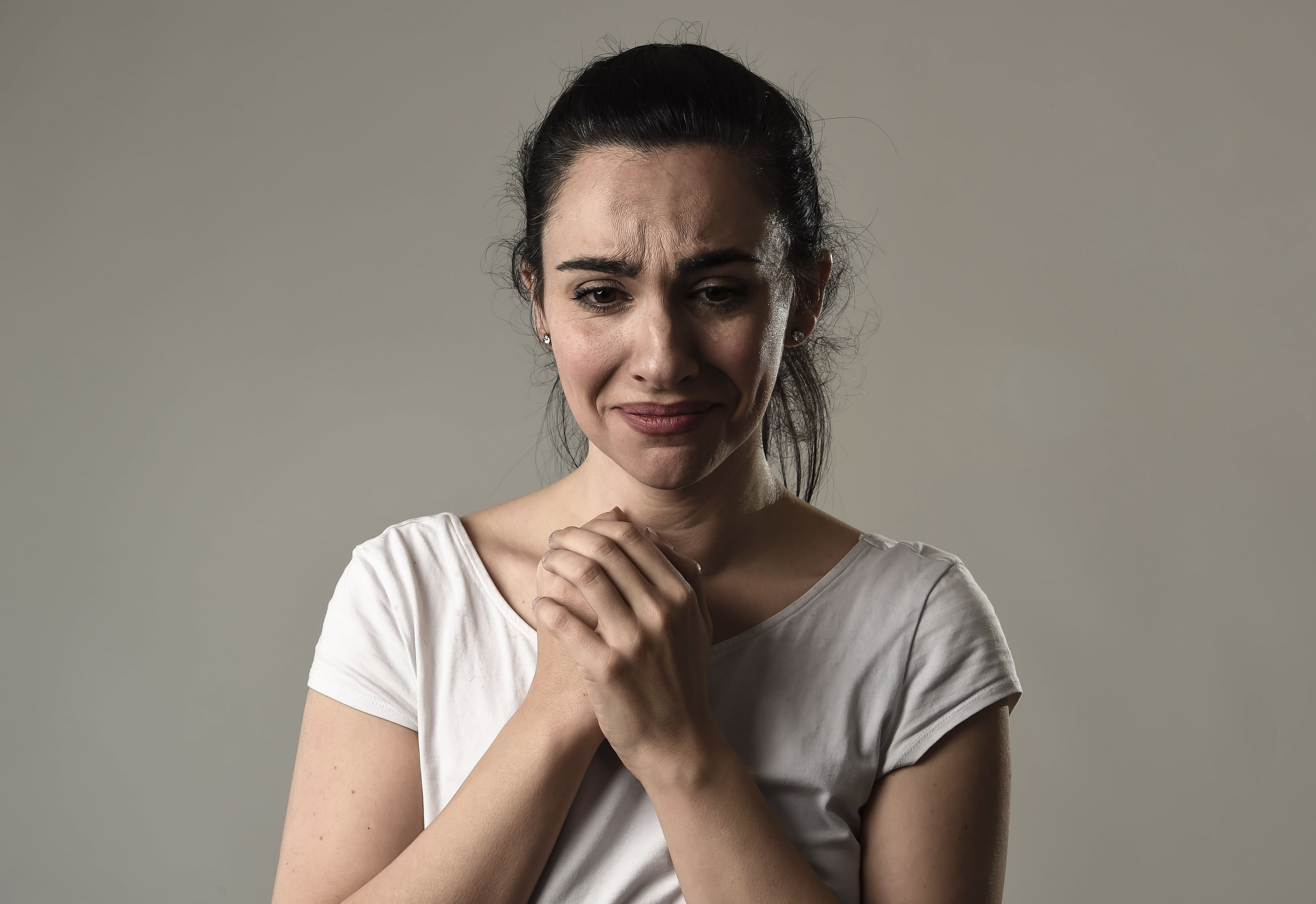 A woman clasps her hands together and shows sadness. | Source: Shutterstock