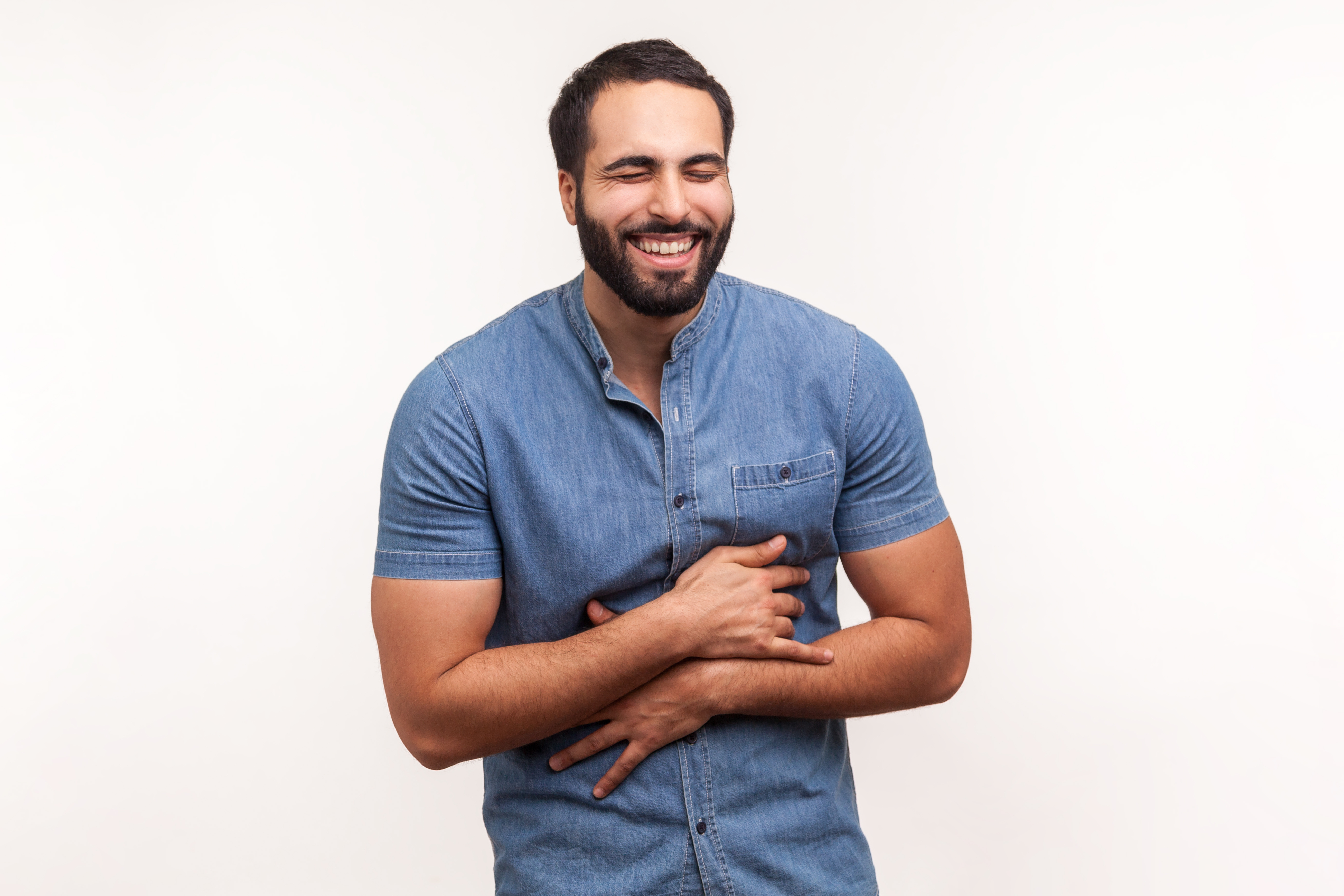 A man holding his abdomen as he laughs | Shutterstock