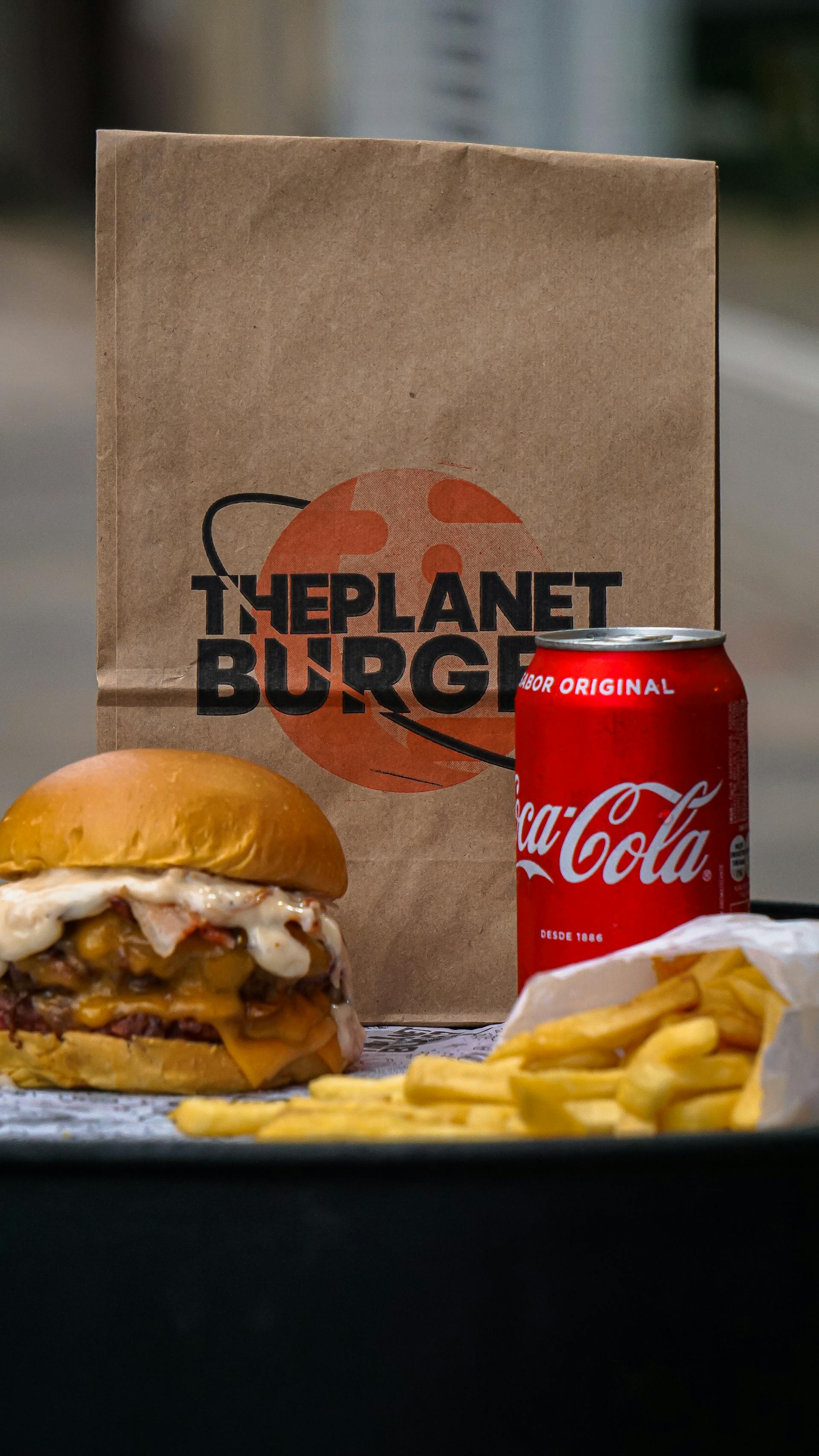 A burger, fries, and a soda can lying next to a paper bag | Source: Pexels