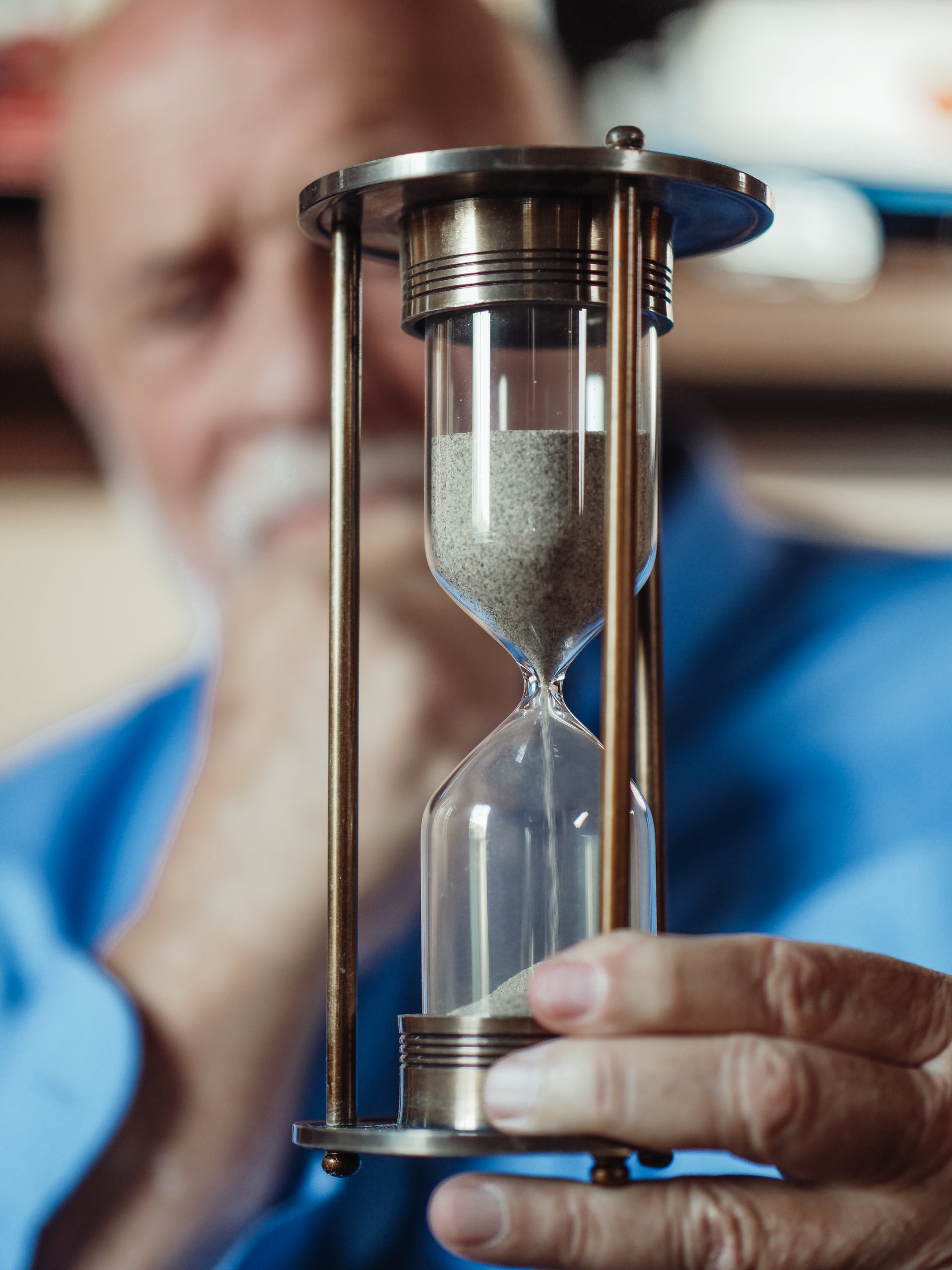 A closeup of a thoughtful senior man holding an hourglass | Source: Pexels