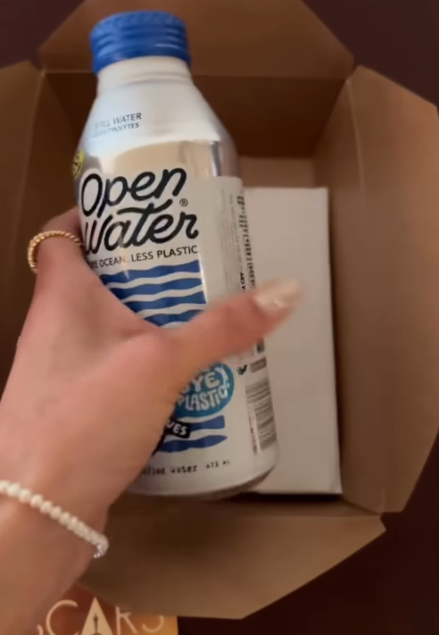 A chilled bottle of Open Water is lifted from the box, its minimalist design suggesting a refreshing break between bites. | Source: Instagram/instylemagazine